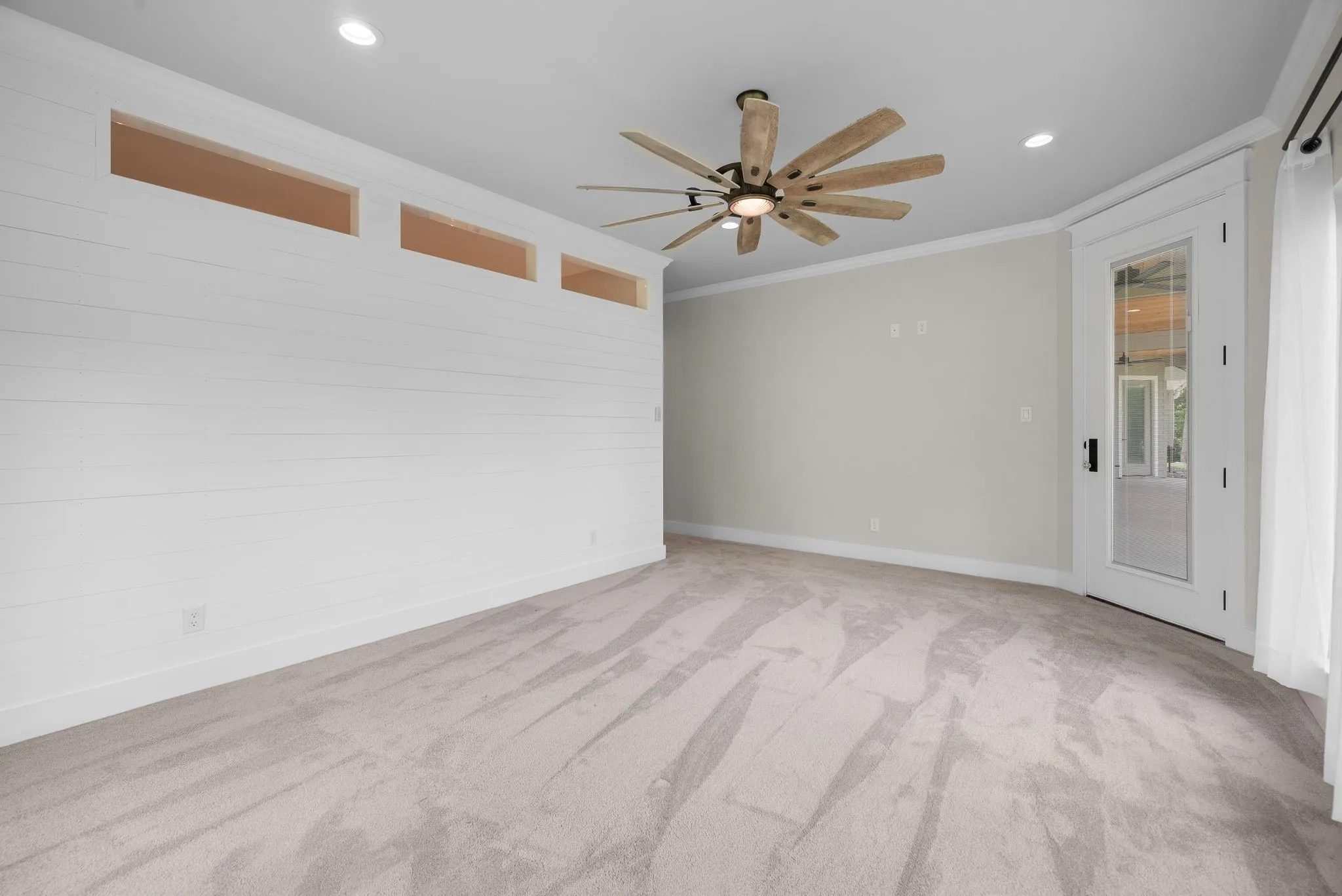 Spacious primary bedroom with ceiling fan, soft carpet, and natural light.