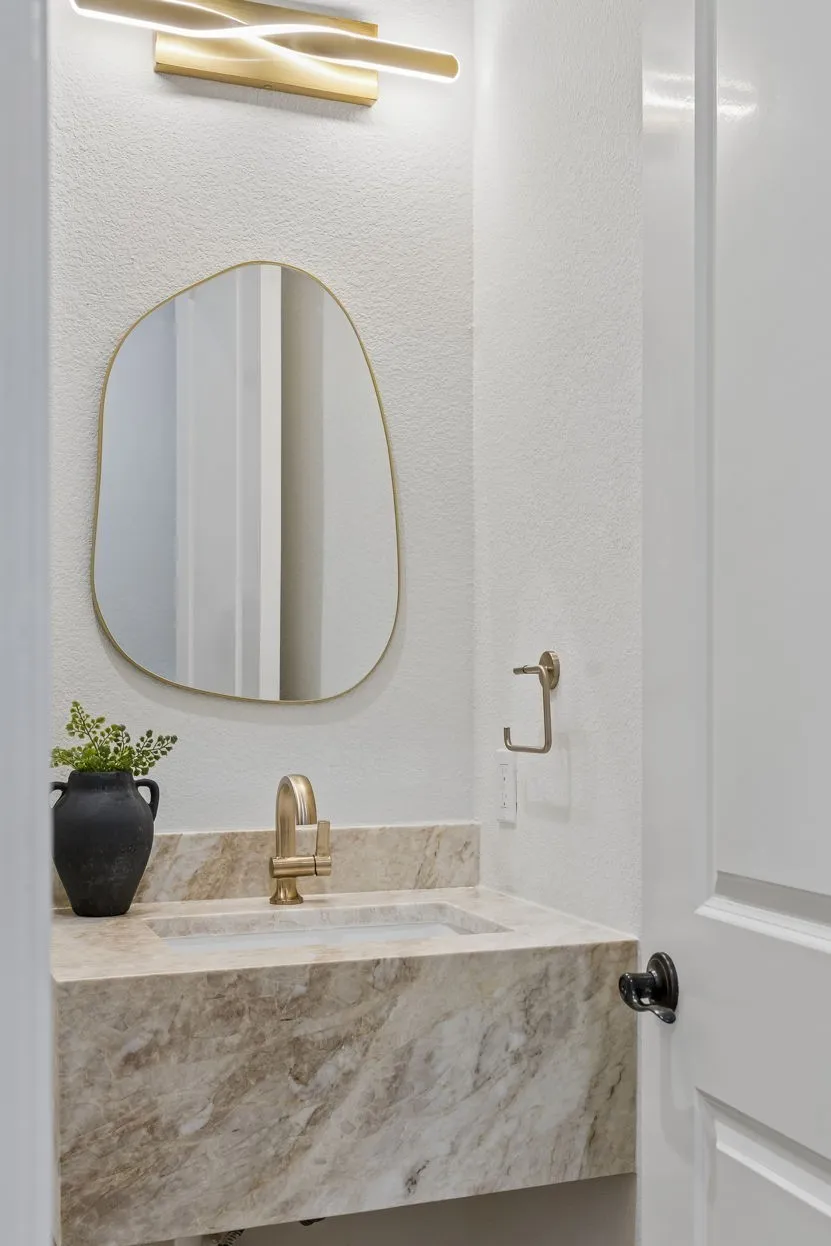 Floating stone vanity with an integrated rectangular sink and brass-finish faucet