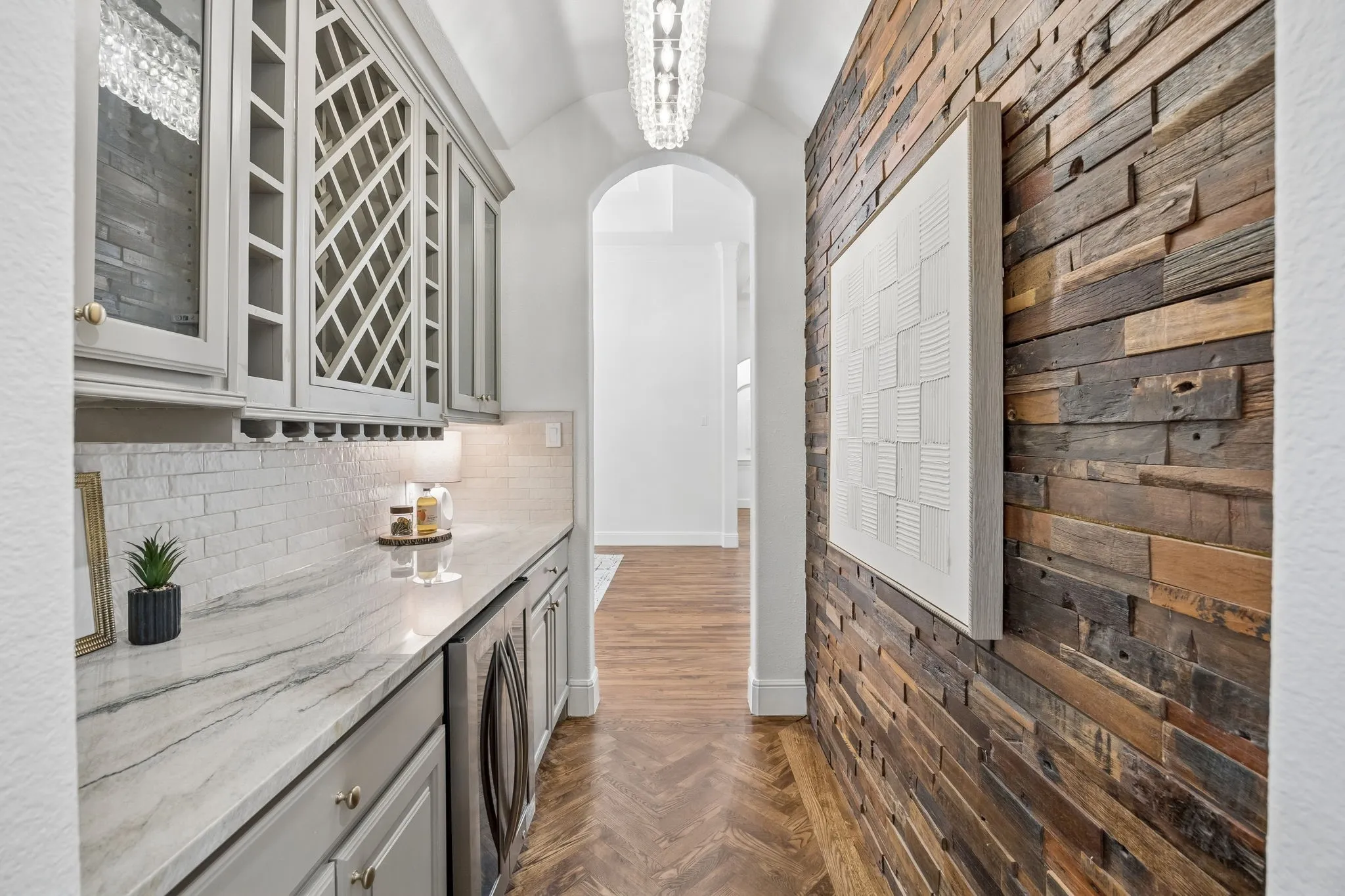 Hallway featuring a built-in beverage bar with light gray cabinetry, integrated wine storage, and a striking stone countertop
