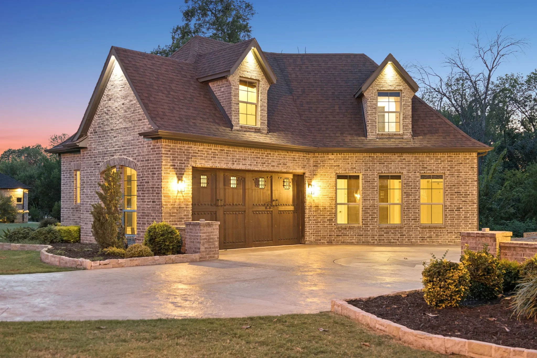 Brick exterior featuring a two-car garage with carriage-style doors and dormer windows