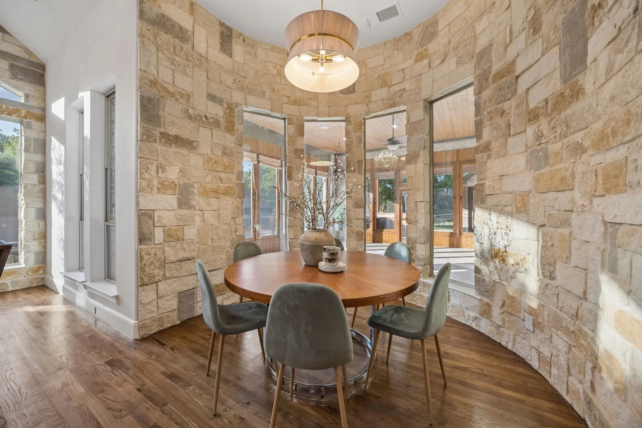 Curved stone wall with integrated windows, wood-finish flooring, and a contemporary ceiling fixture