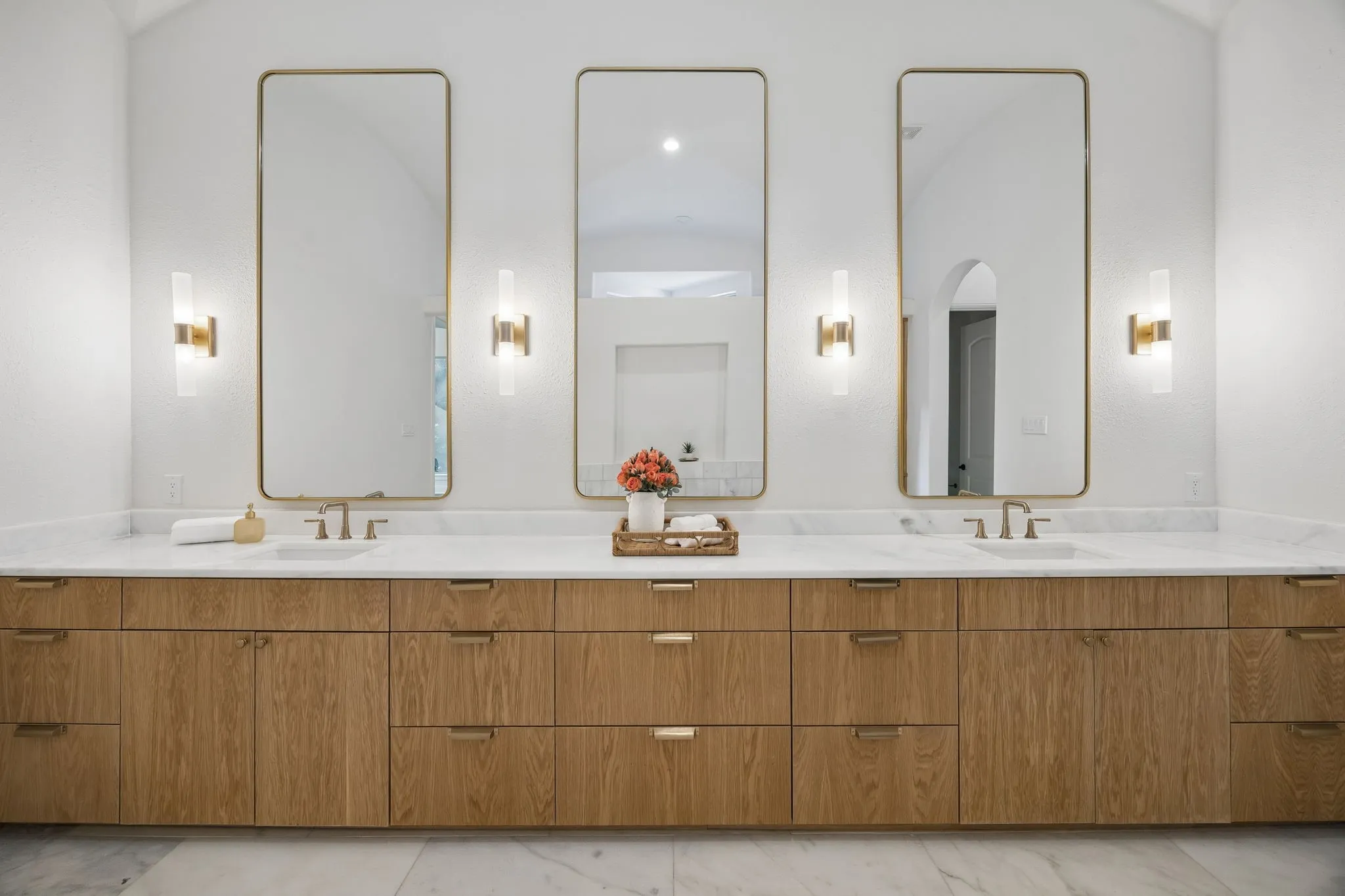 Spacious double vanity with light wood cabinetry and integrated brass hardware