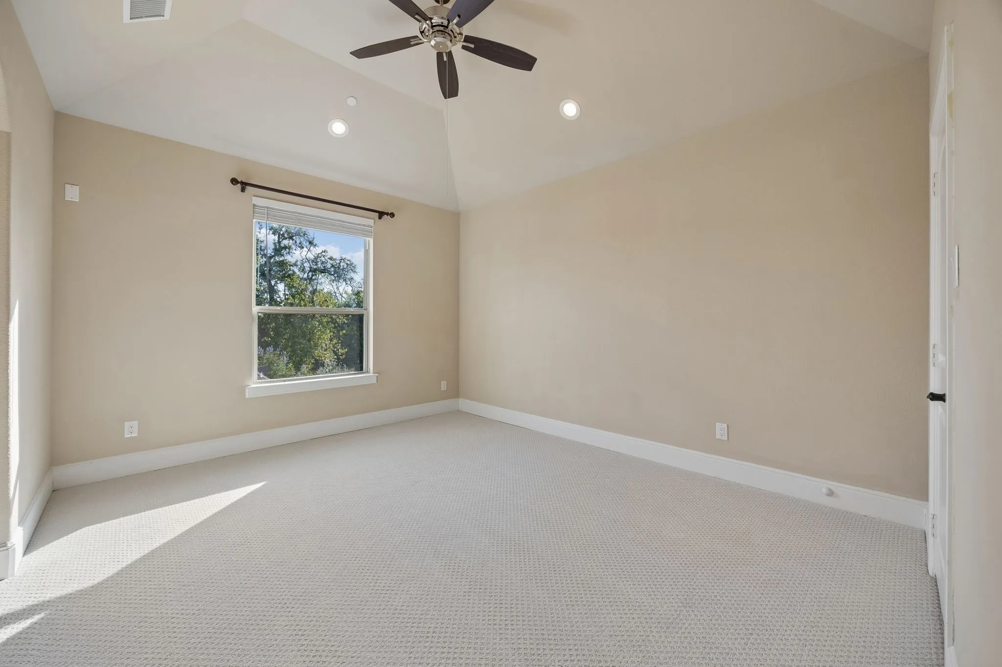 Spacious room featuring vaulted ceilings, recessed lighting, and a ceiling fan
