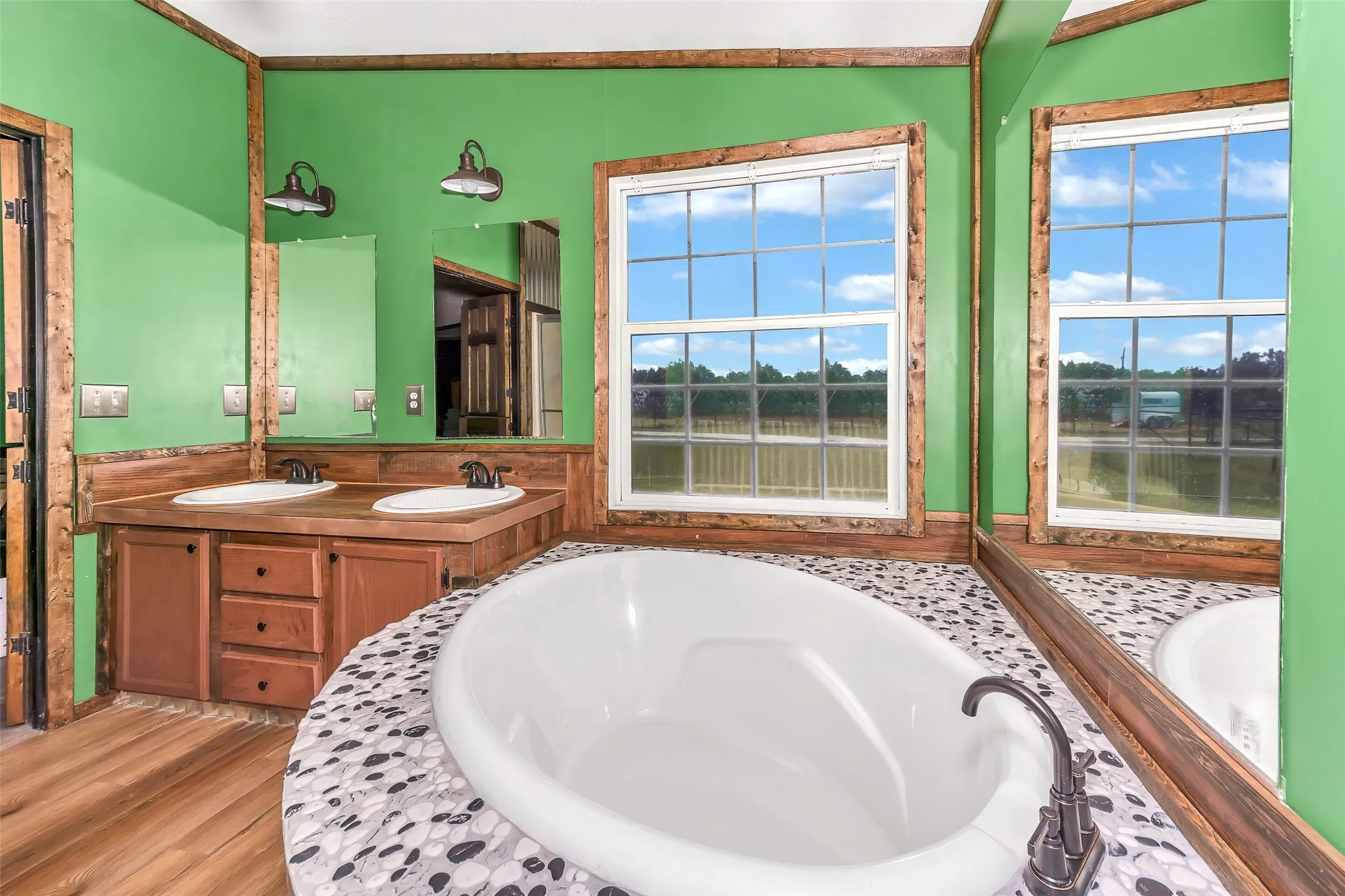 Freestanding oval soaking tub set on a pebble-tiled platform