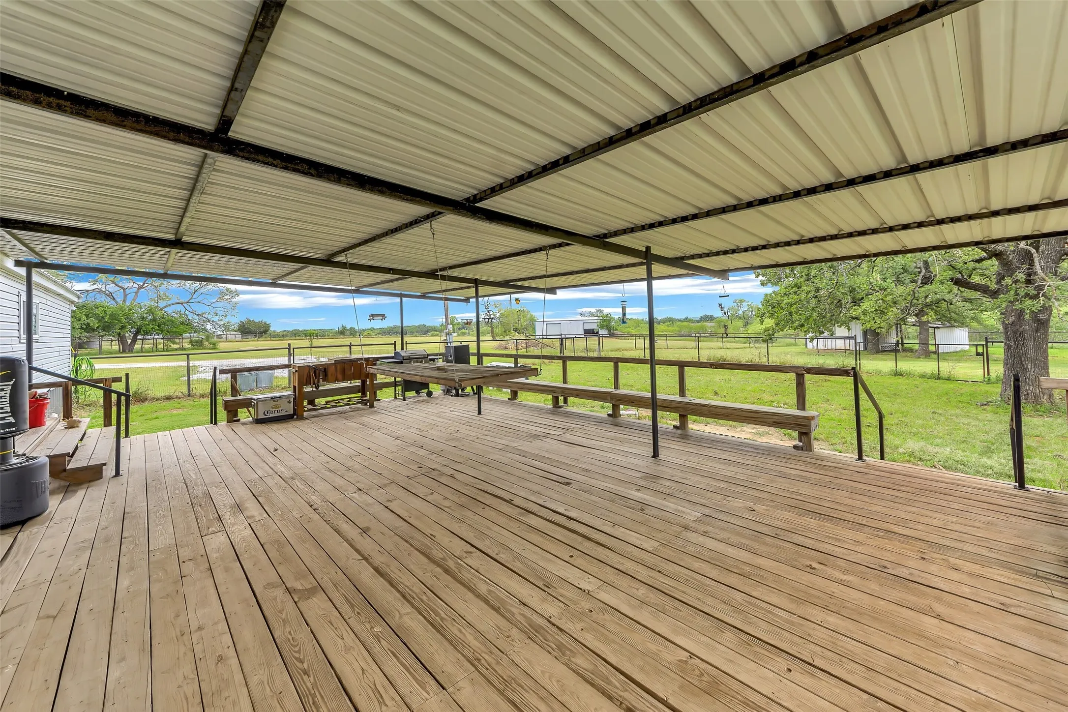Expansive wood-finish deck featuring a full-coverage metal roof and black metal railings