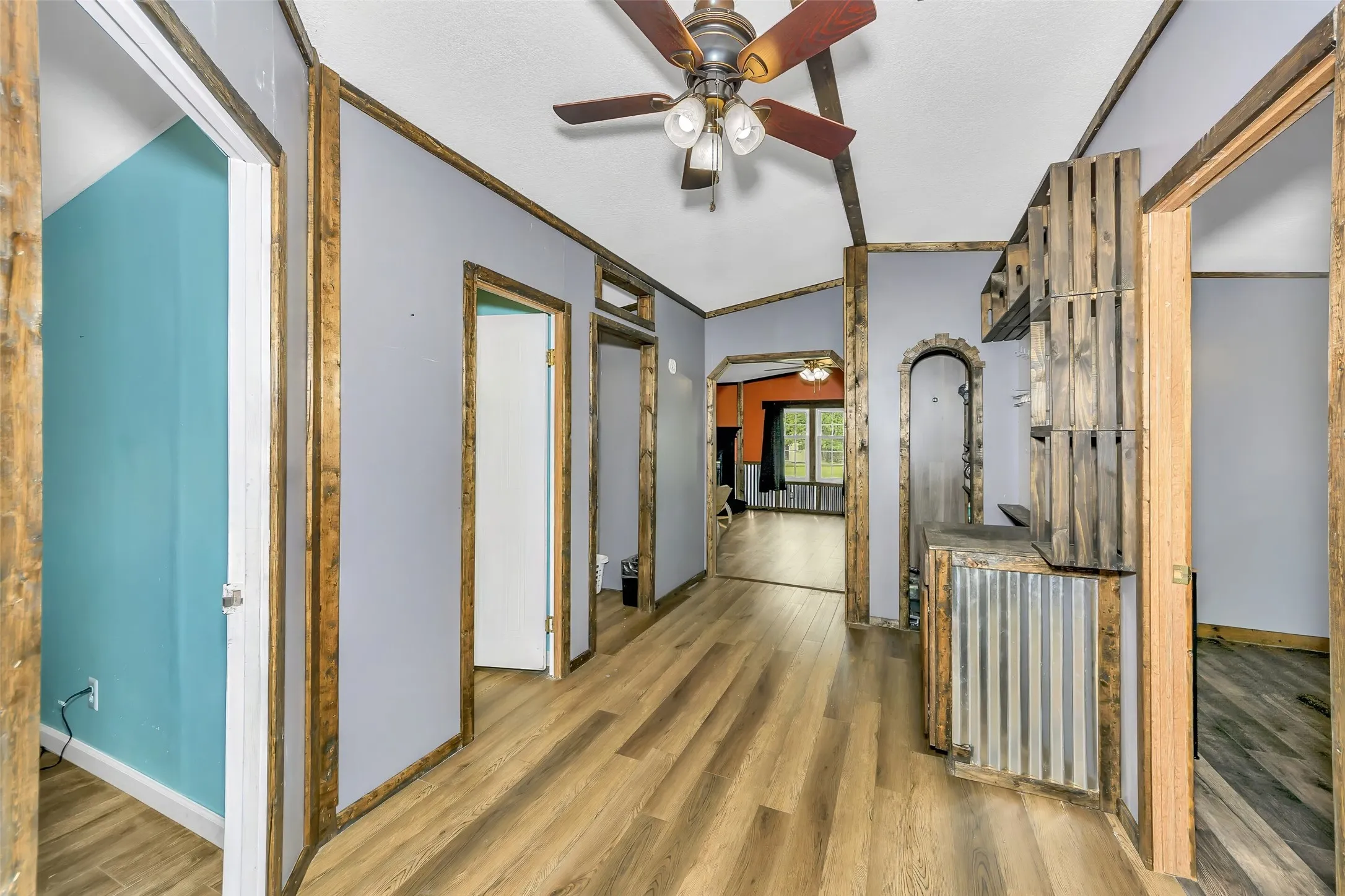 Interior hallway featuring wood-finish flooring, light gray walls with wood trim accents, and a ceiling fan