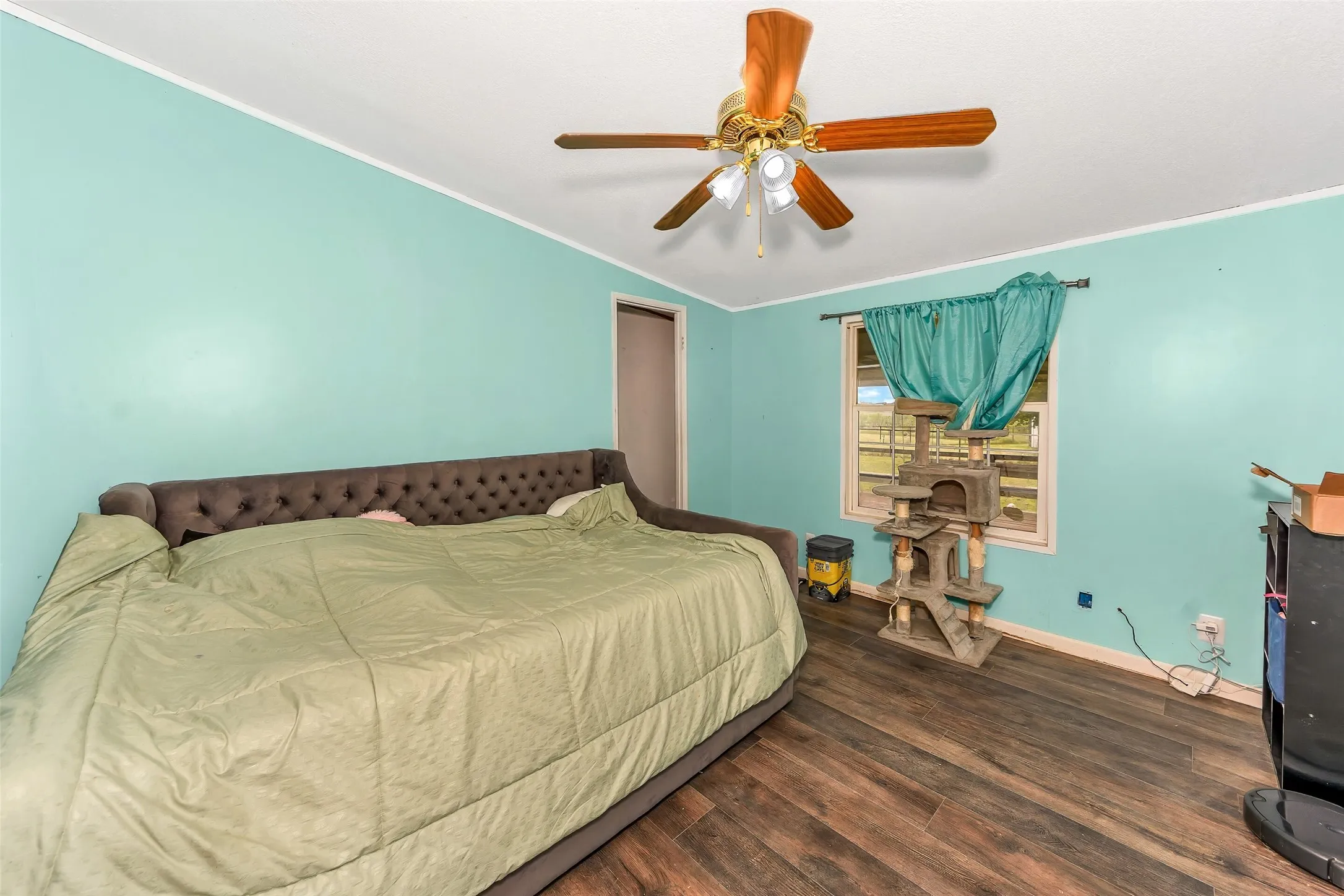 Spacious room featuring wood-finish flooring, a ceiling fan with light fixture, and a window providing natural light