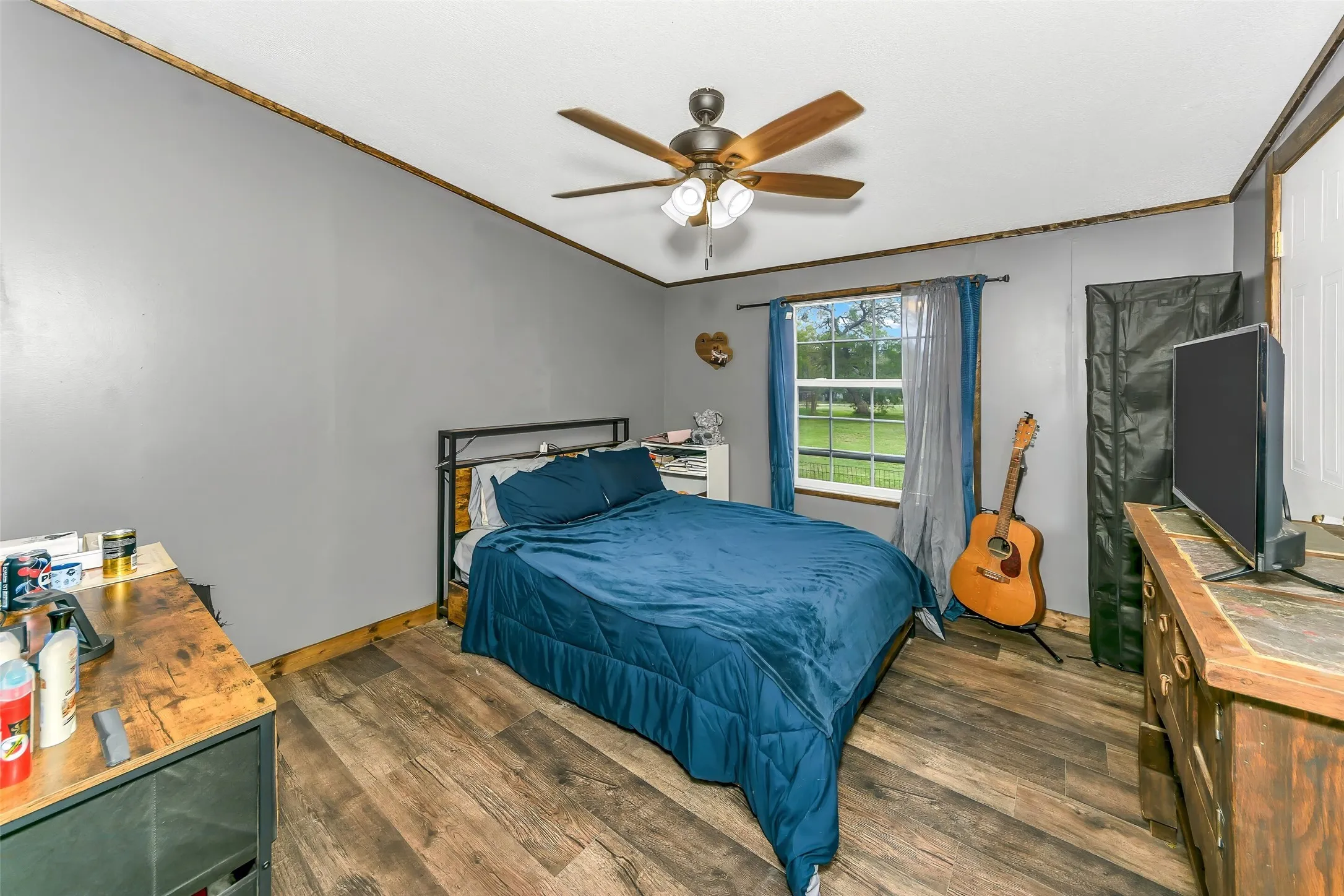 Bedroom featuring wood-finish flooring, a ceiling fan with integrated lighting, and a window with exterior views