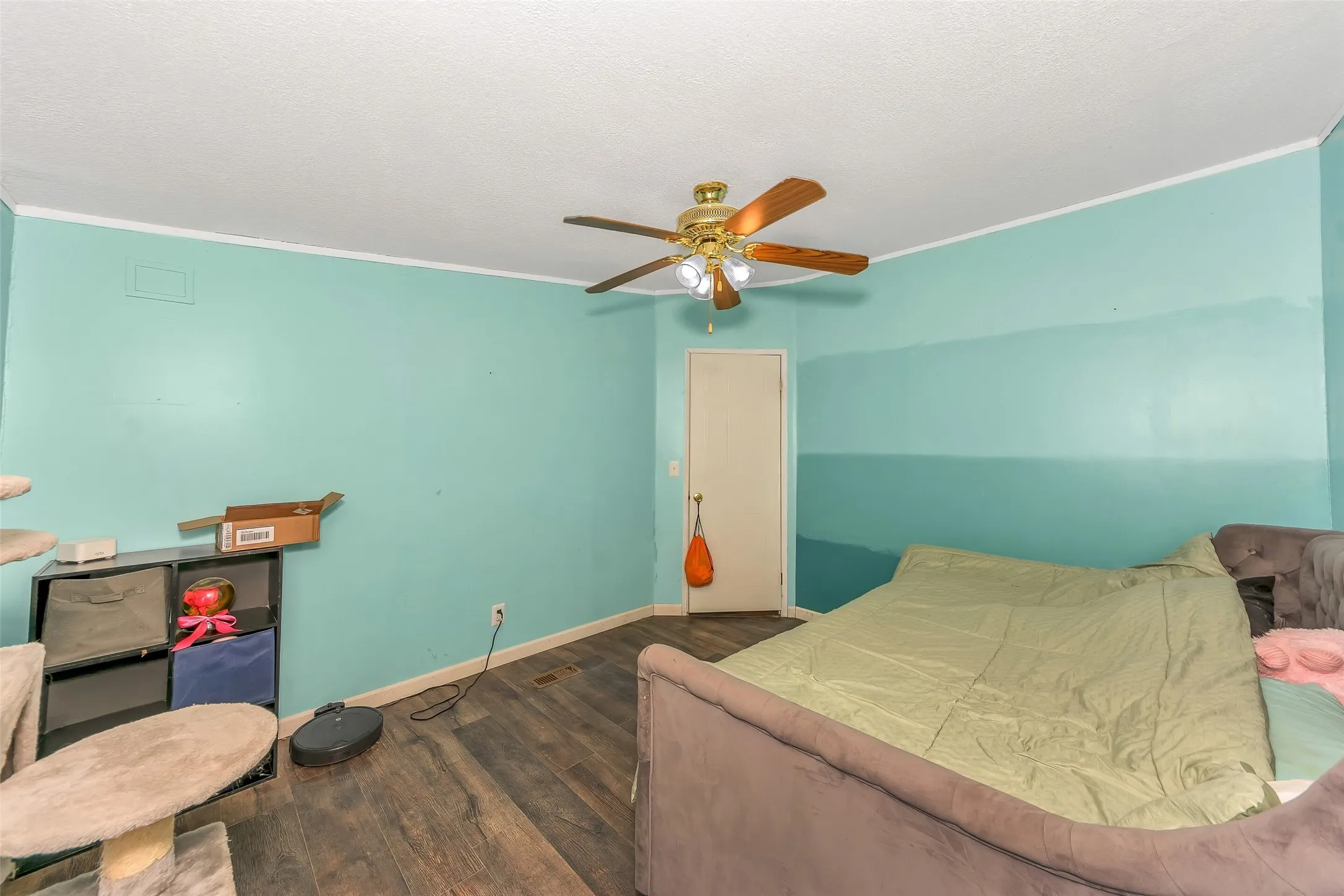 Room featuring wood-finish flooring, a ceiling fan with integrated lighting, and a white interior door