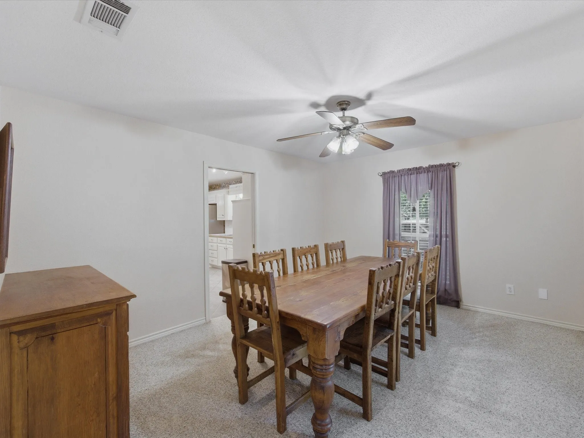 Dining room with ceiling fan and window just off kitchen and front entry