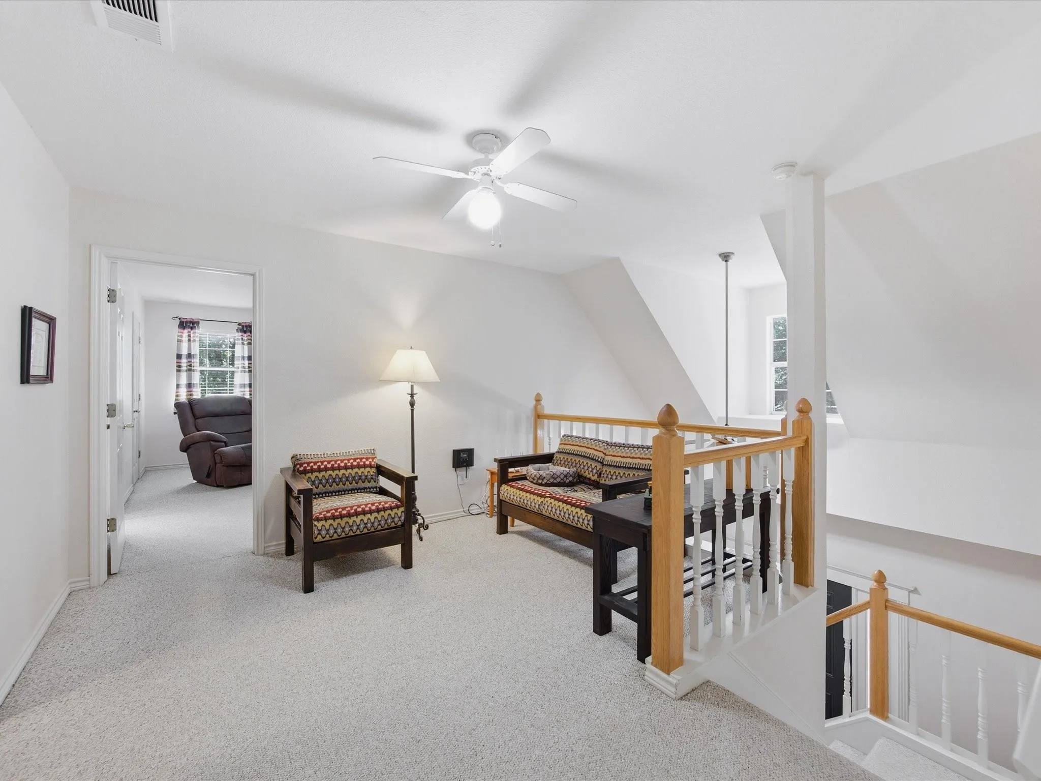 Loft sitting area with ceiling fan and dormer window