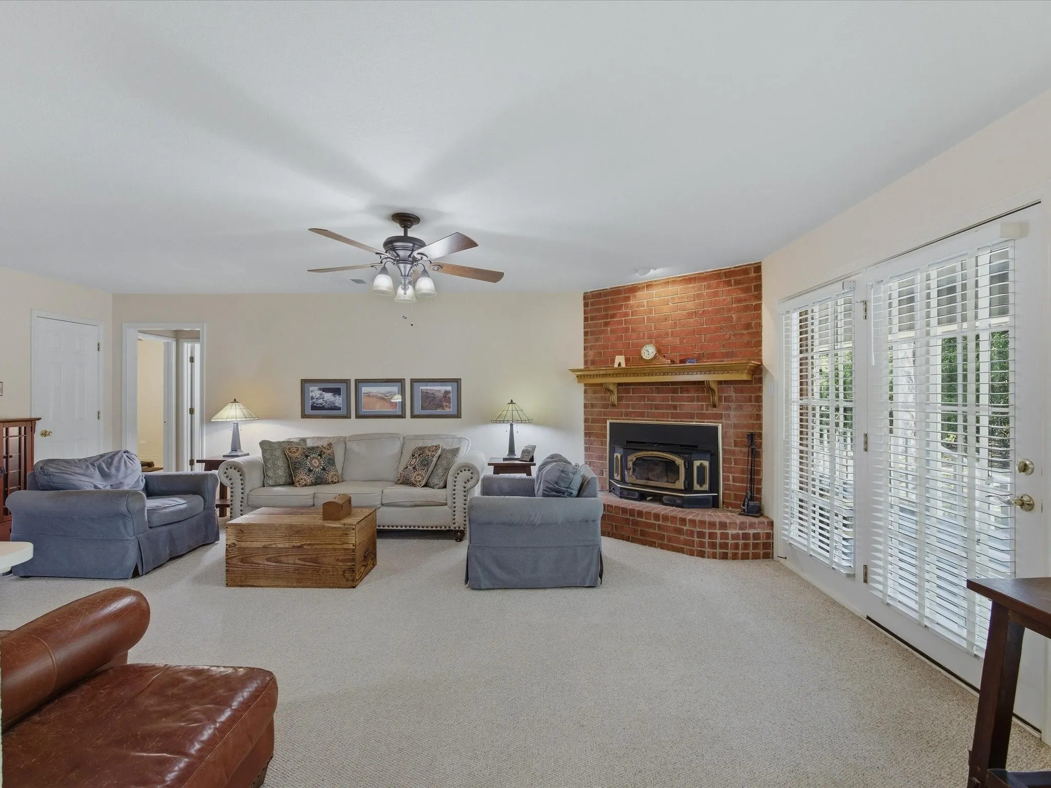 Large living room area with ceiling fan, lots of natural light and patio door to covered porch with window coverings. Decorative gas fireplace insert (wood) fireplace makes perfect warm and cozy ambiance on colder nights.