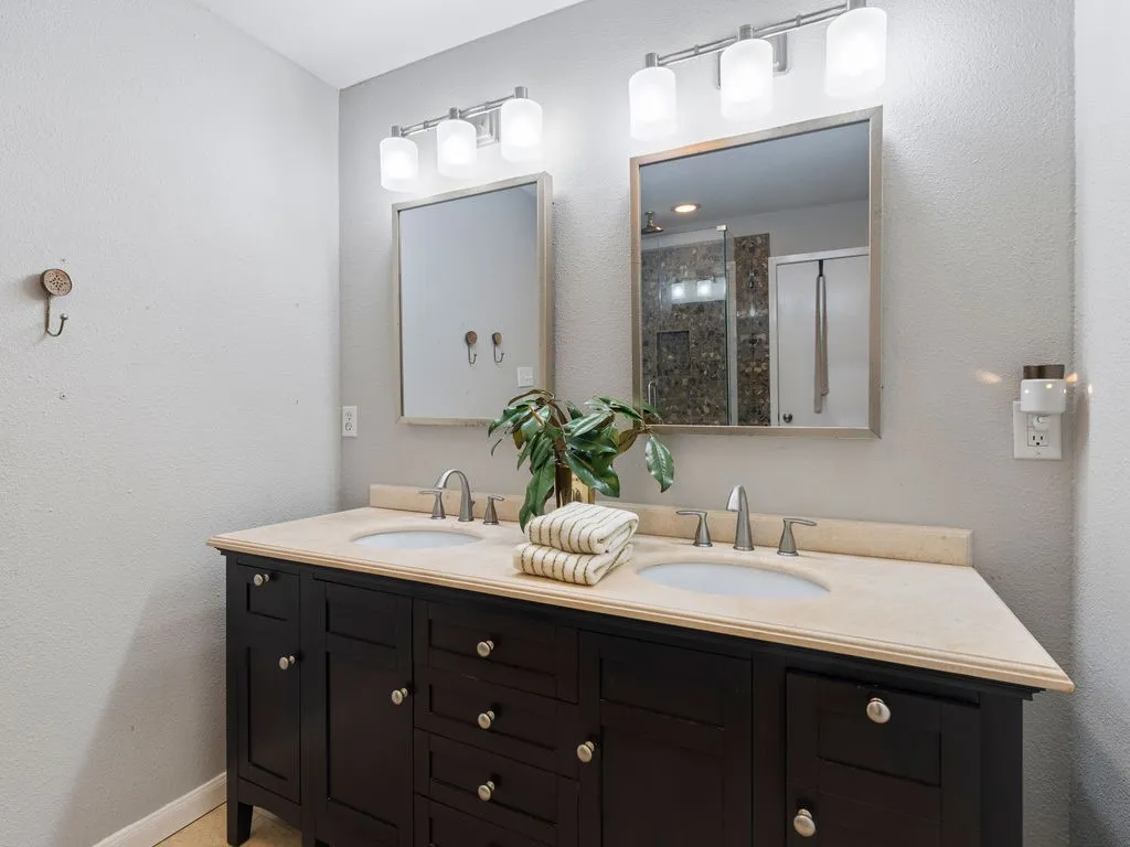 Double vanity featuring a dark wood-finish cabinet with multiple drawers and doors, dual undermount sinks, and a light-toned countertop