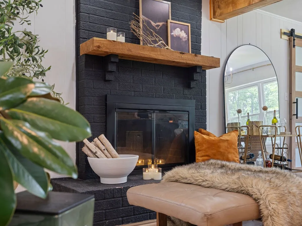 Black brick fireplace with a wood-beam mantel and a built-in fireplace insert