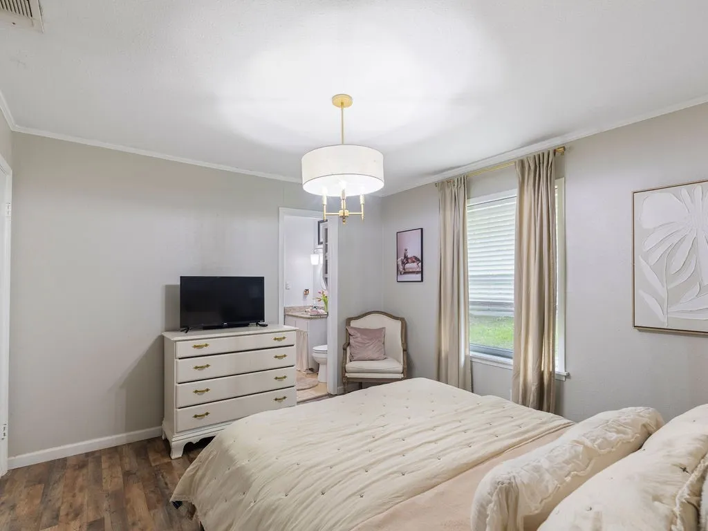 Bedroom featuring wood-finish flooring, a contemporary drum pendant light fixture, and crown molding
