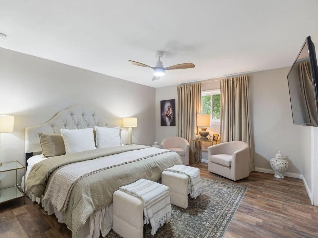 Bedroom featuring wood-finish flooring, a ceiling fan with integrated lighting, and a window with natural light