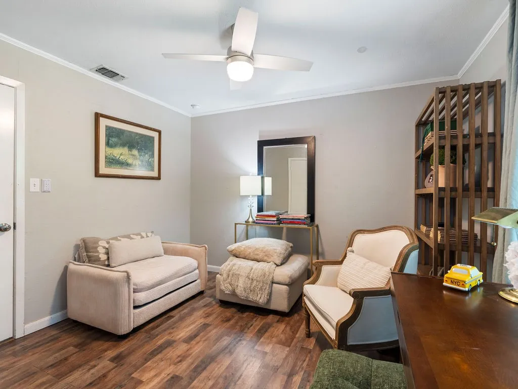 Spacious room featuring wood-finish flooring, light gray wall paint, and white crown molding