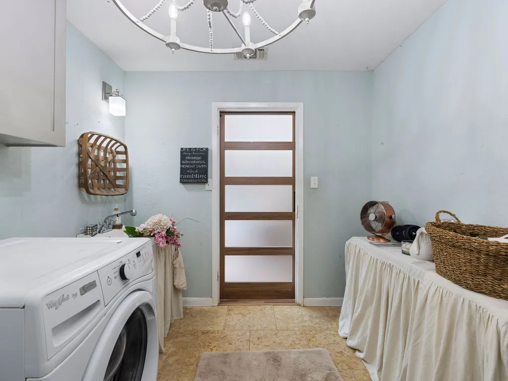 Laundry area featuring a contemporary paneled door with frosted glass inserts, a utility sink with a chrome faucet, and tile flooring