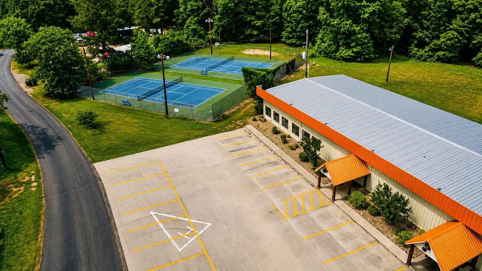 Two blue tennis courts with green perimeter fencing and light poles