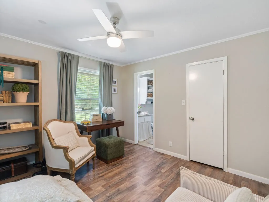 Wood-finish flooring, light gray wall paint, and a ceiling fan with integrated lighting
