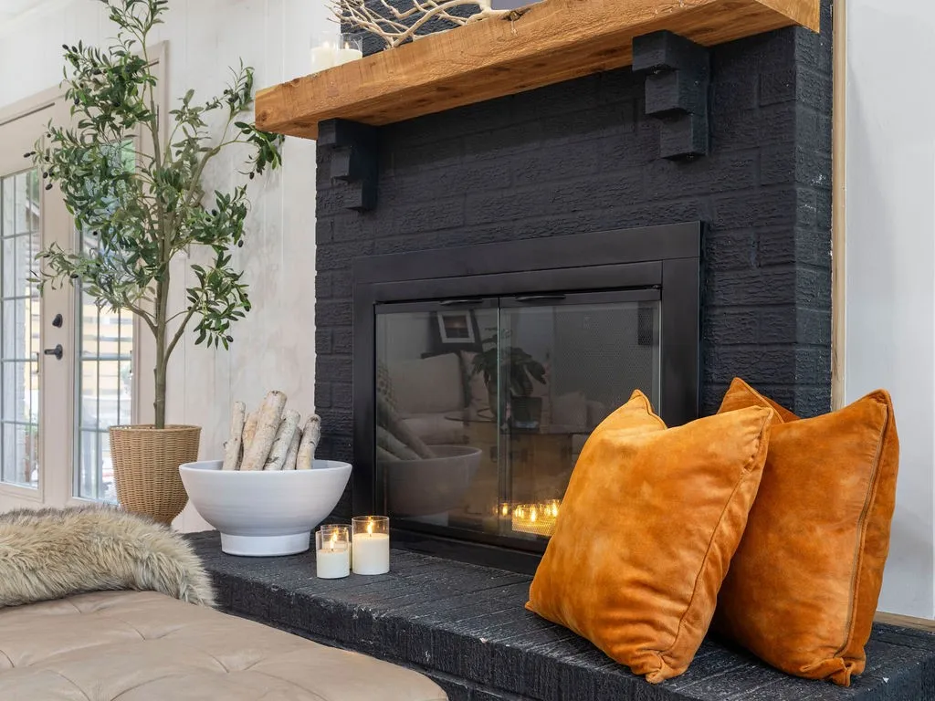 Fireplace featuring a black brick surround, a black hearth, and a substantial wood mantel