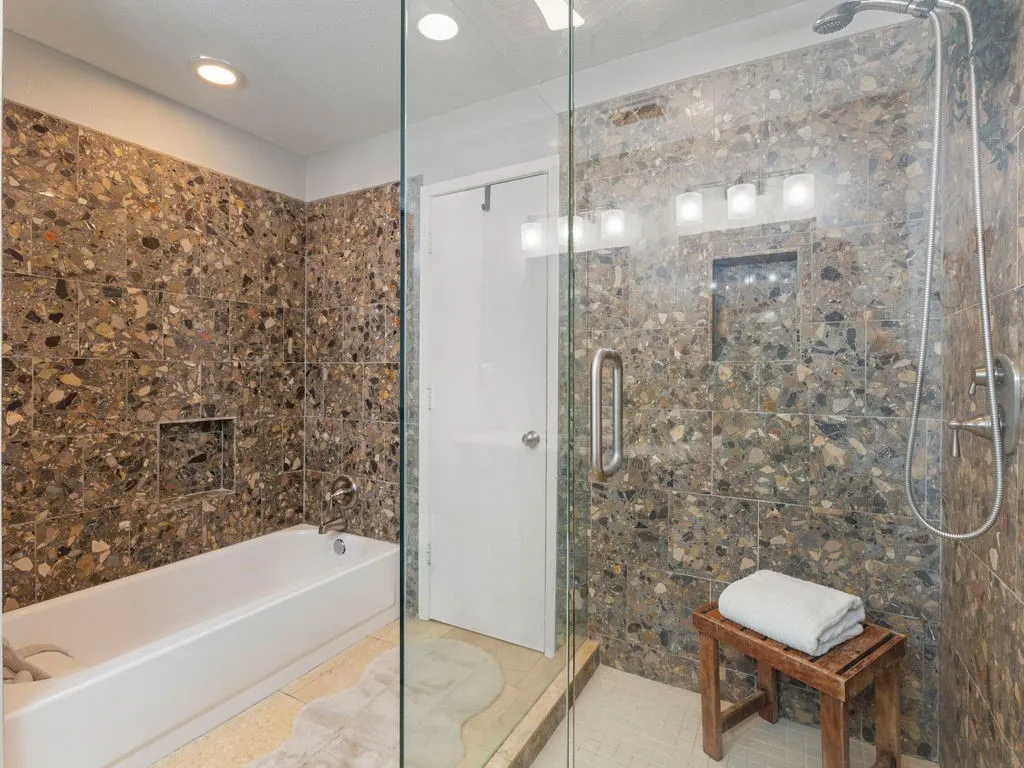 Bathroom featuring a glass-enclosed shower with a handheld shower fixture, a built-in shower niche, a full-size bathtub with a built-in niche, and recessed ceiling lighting