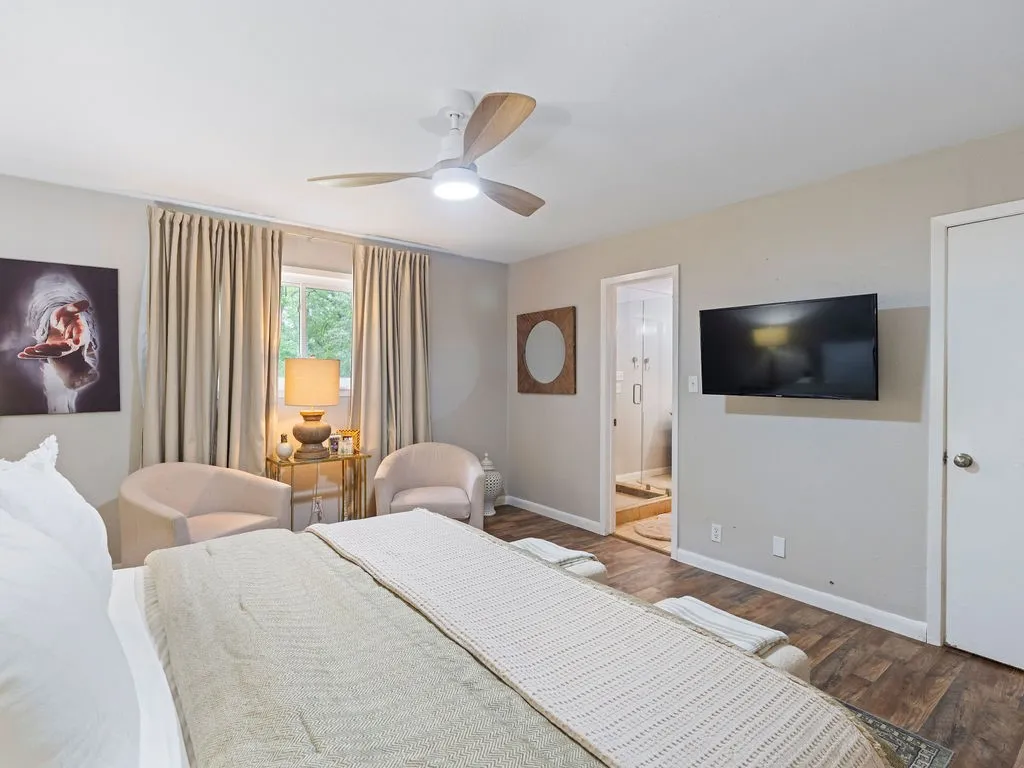 Spacious room featuring wood-finish flooring, a contemporary ceiling fan with integrated lighting, and a window with natural light