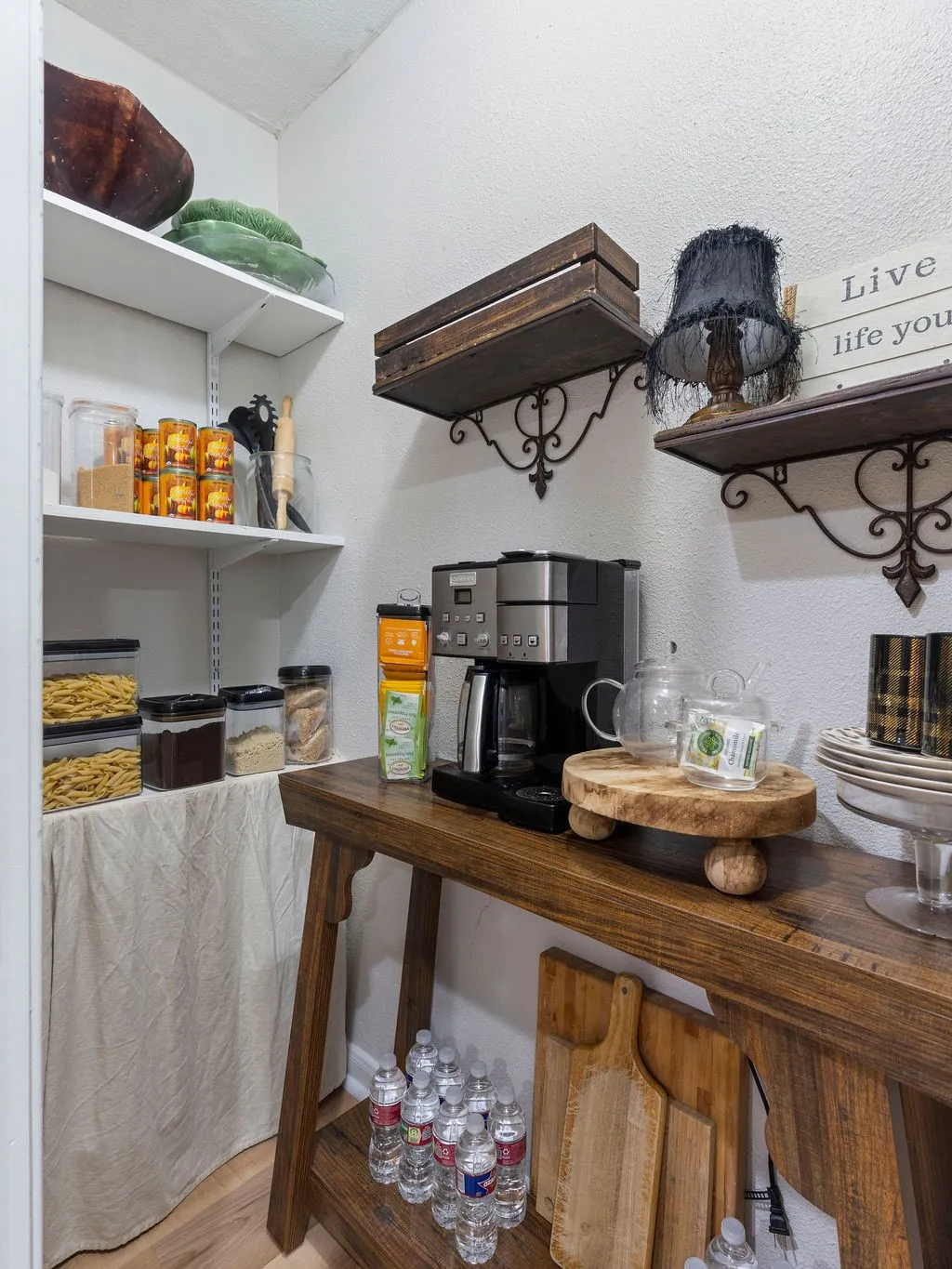 Utility nook featuring a wood-finish console table, two wall-mounted decorative shelves with ornate brackets, and white adjustable shelving