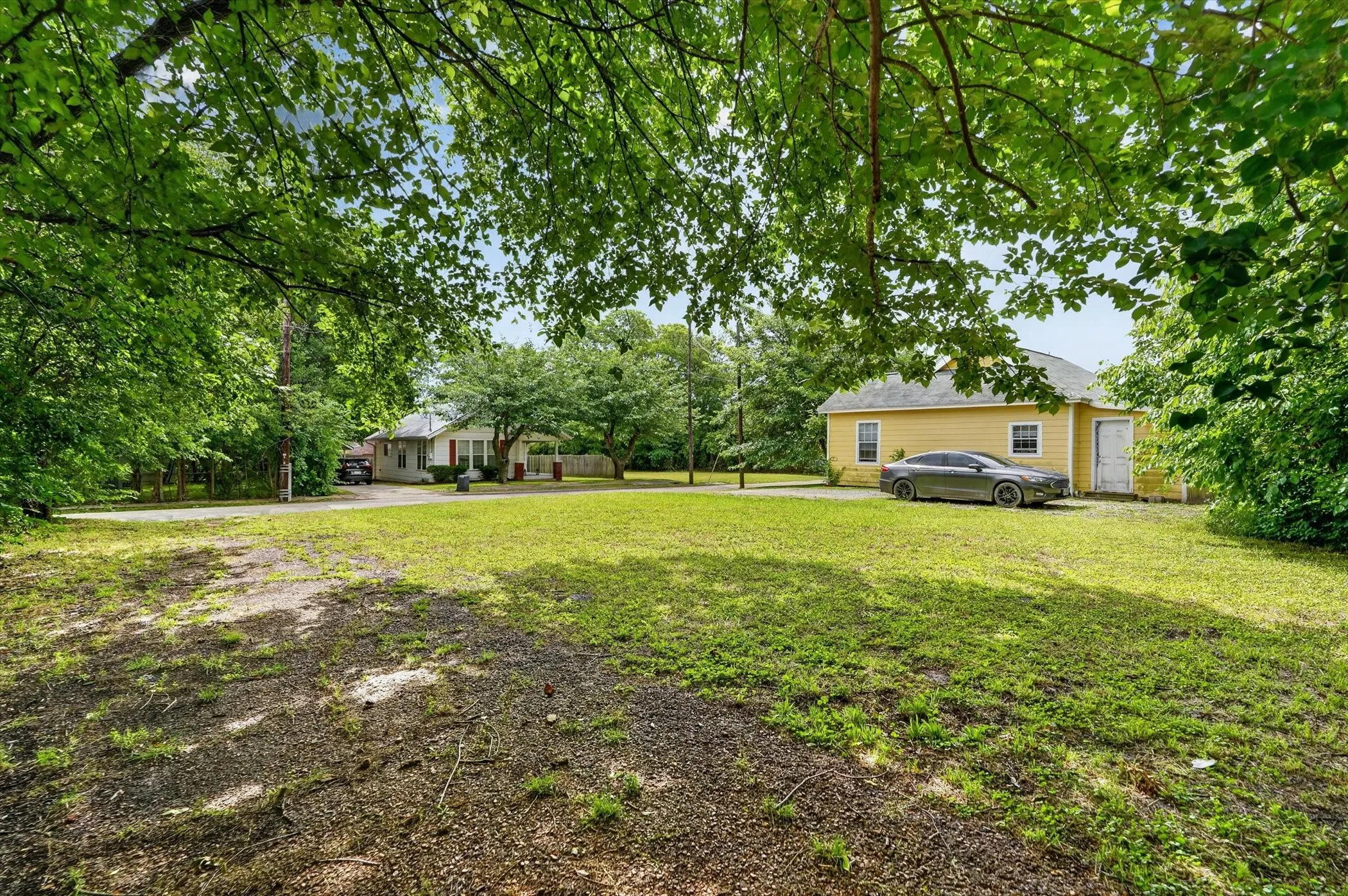 Expansive lot featuring a large grassy area, mature trees, and natural landscaping