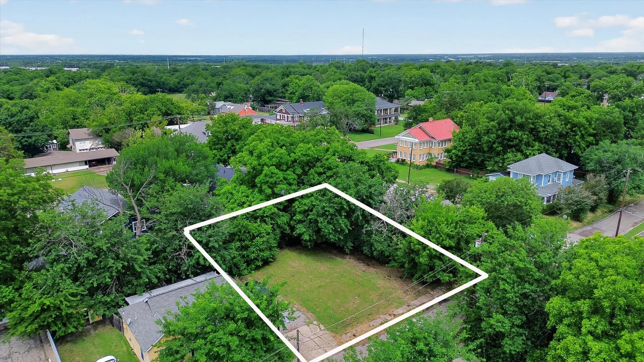 Expansive parcel featuring a grassy area surrounded by mature trees. Outline is approximate.