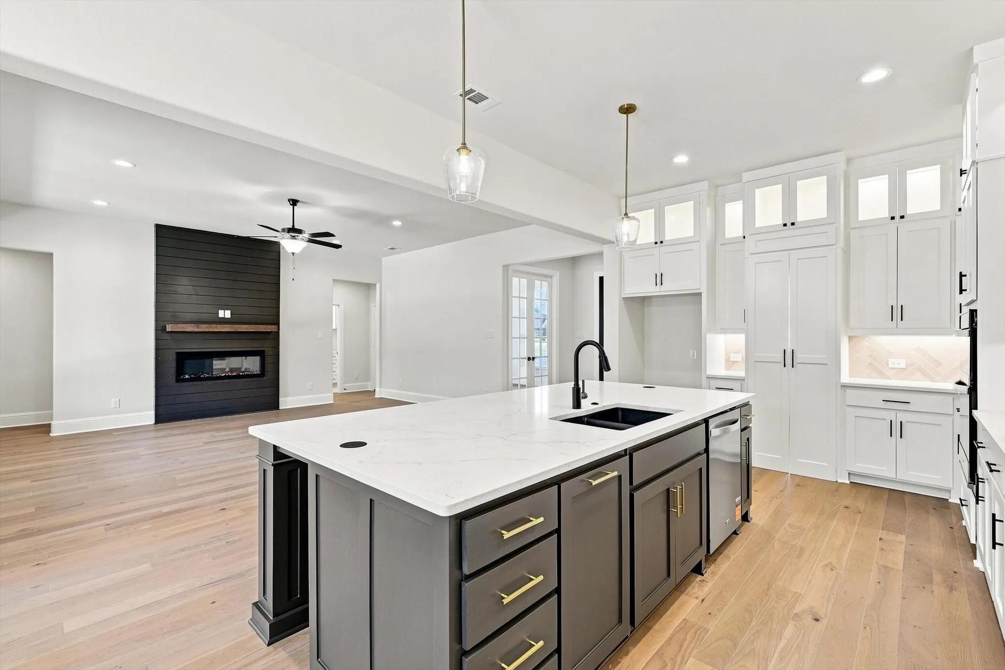 Open-concept kitchen and living area featuring a large center island with a built-in sink, stainless steel dishwasher, and quartz countertop