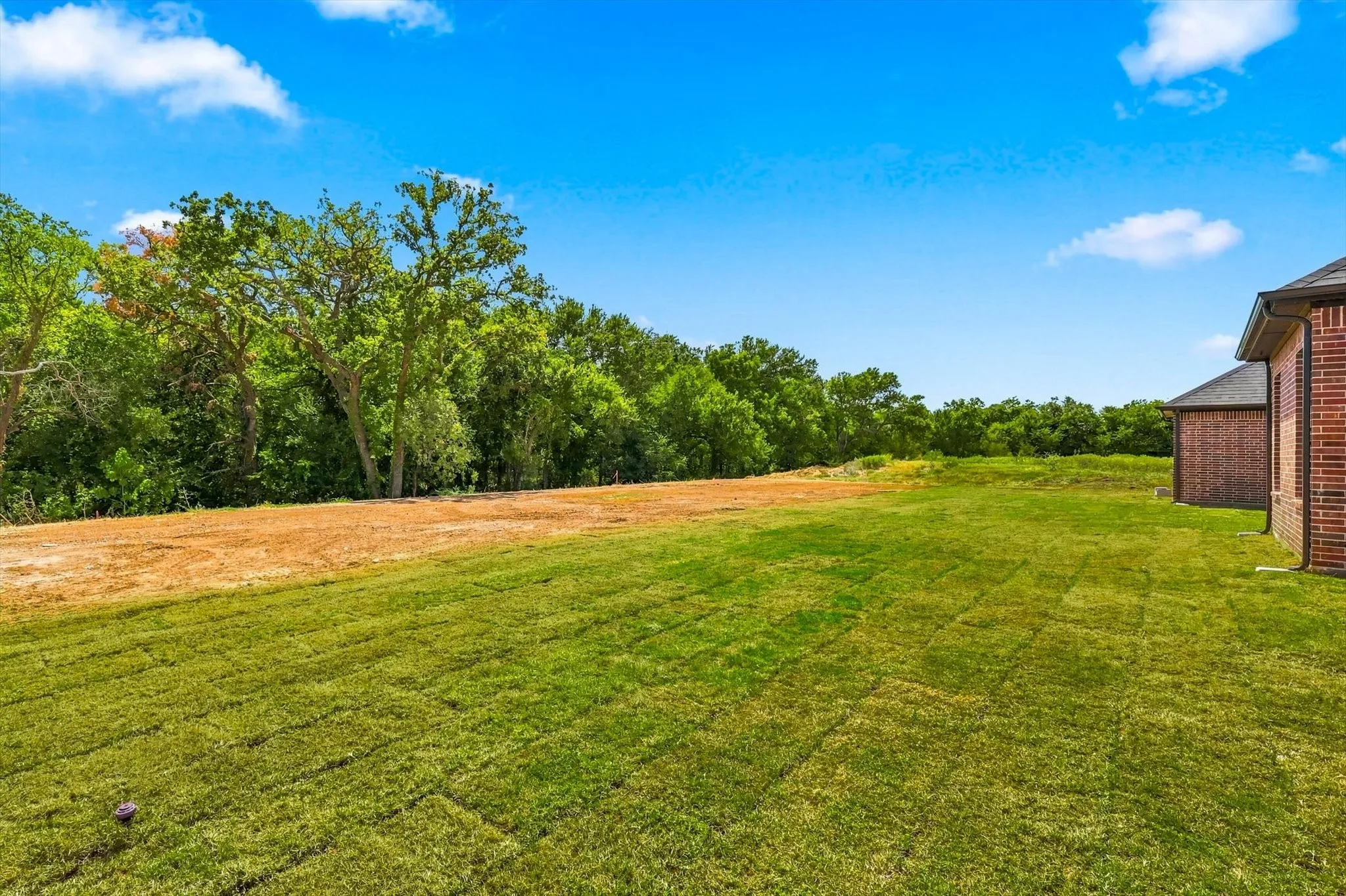 Expansive green lawn with mature trees and brick exterior