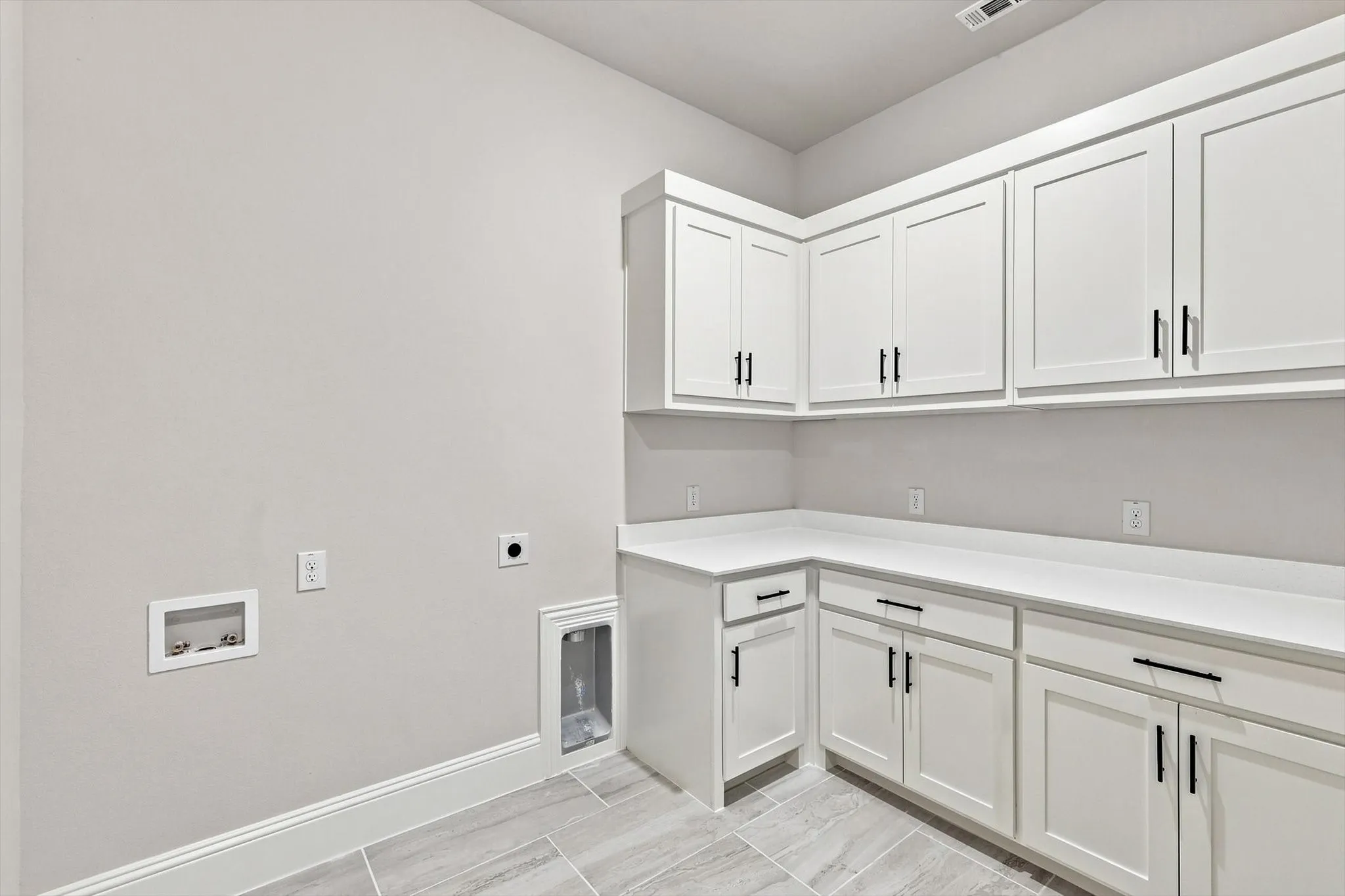 White shaker-style cabinetry with matte black hardware, expansive countertop space, and tile flooring