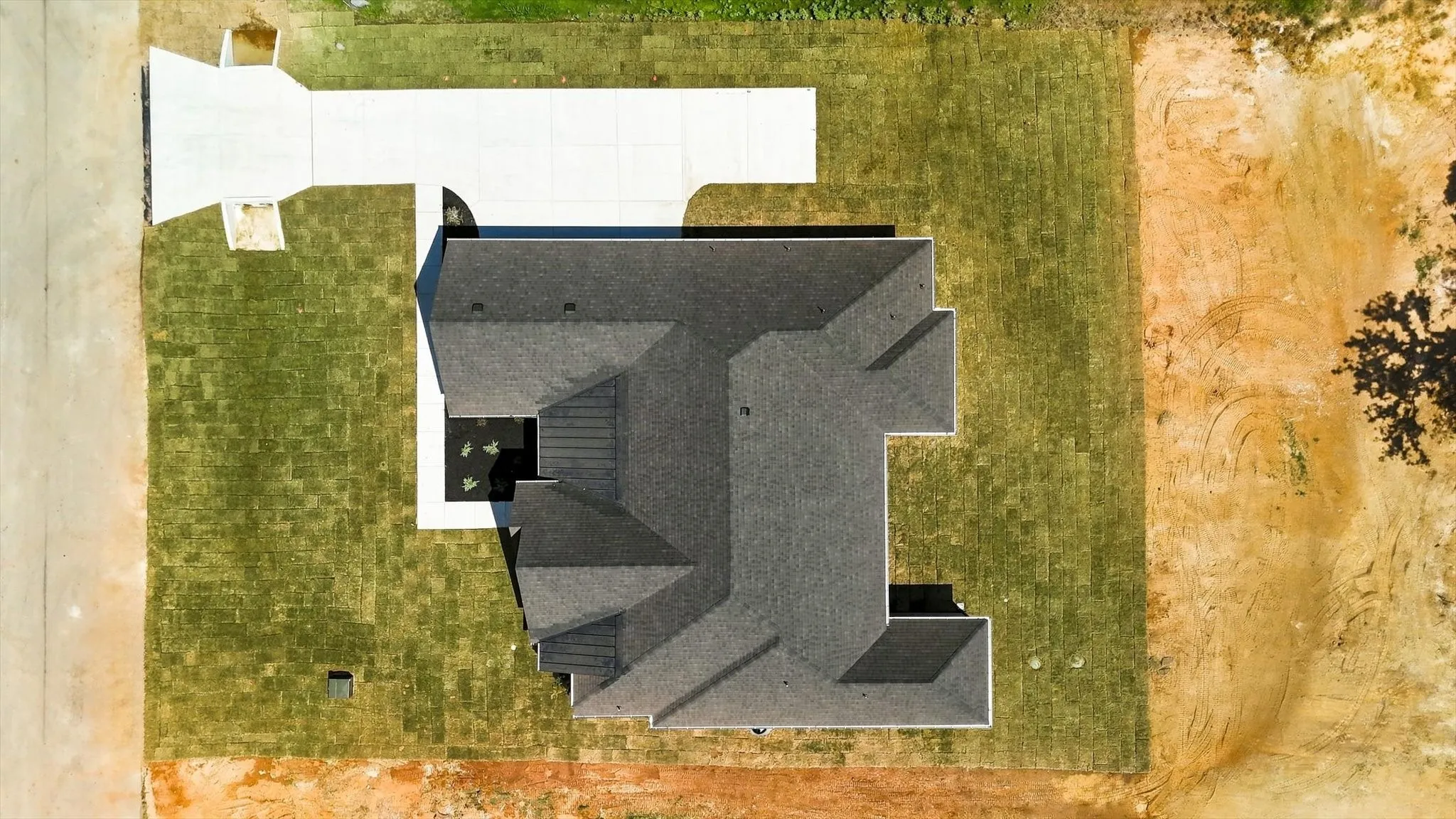 New construction with a dark shingle roof, concrete driveway, and established lawn