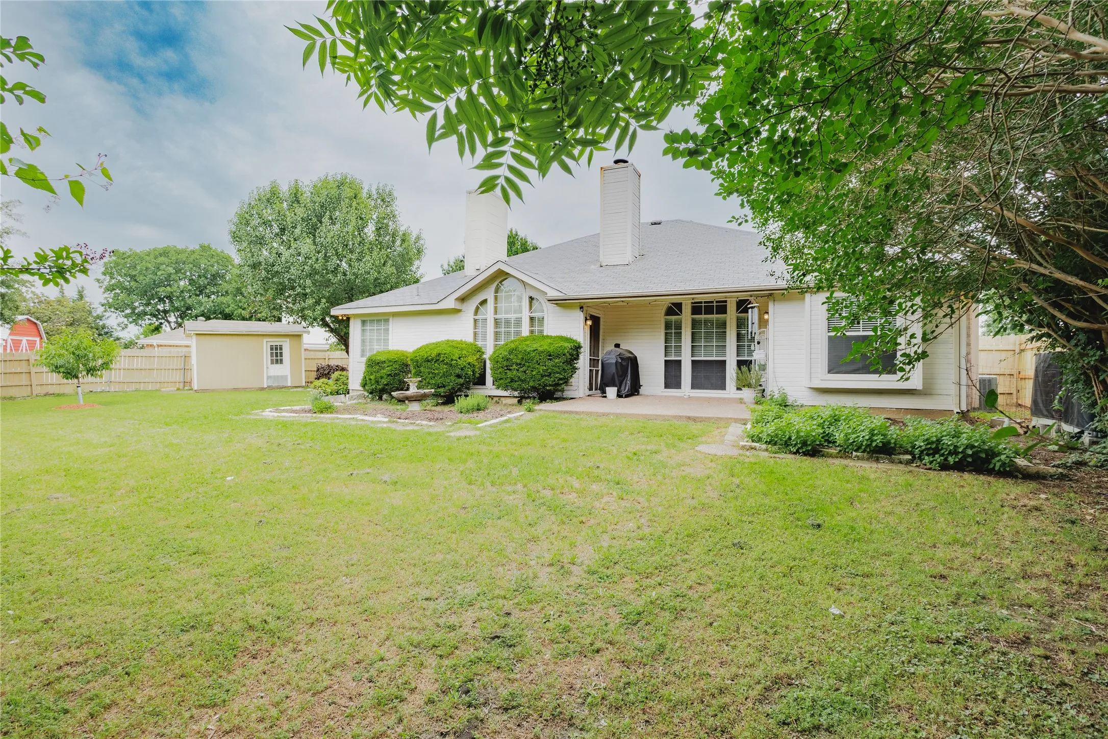 Expansive backyard with a manicured lawn, a privacy fence, and mature trees
