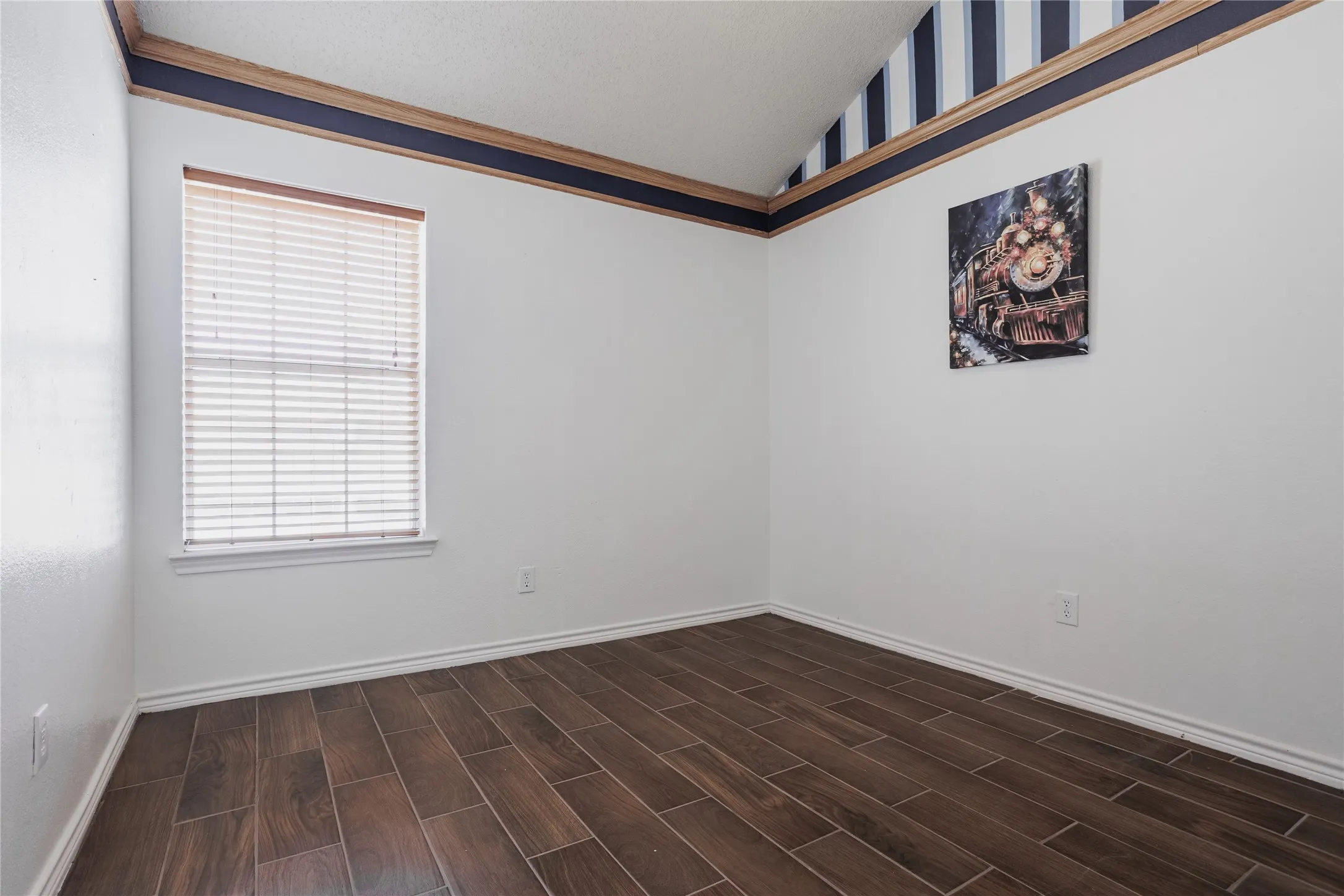 Wood-finish plank flooring, vaulted ceiling, and window with blinds
