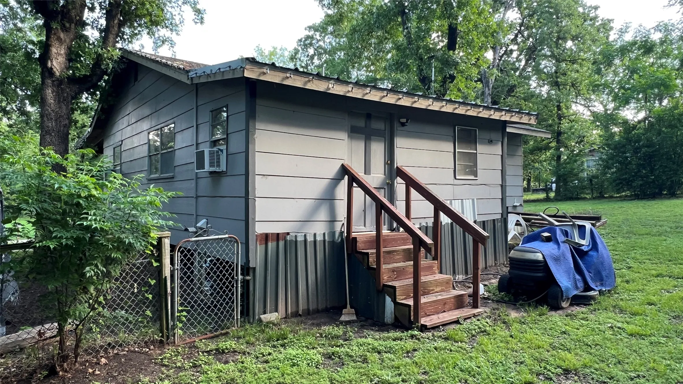 Back of home with wood stairs providing access to the Mudroom-Utility room and rest of house
