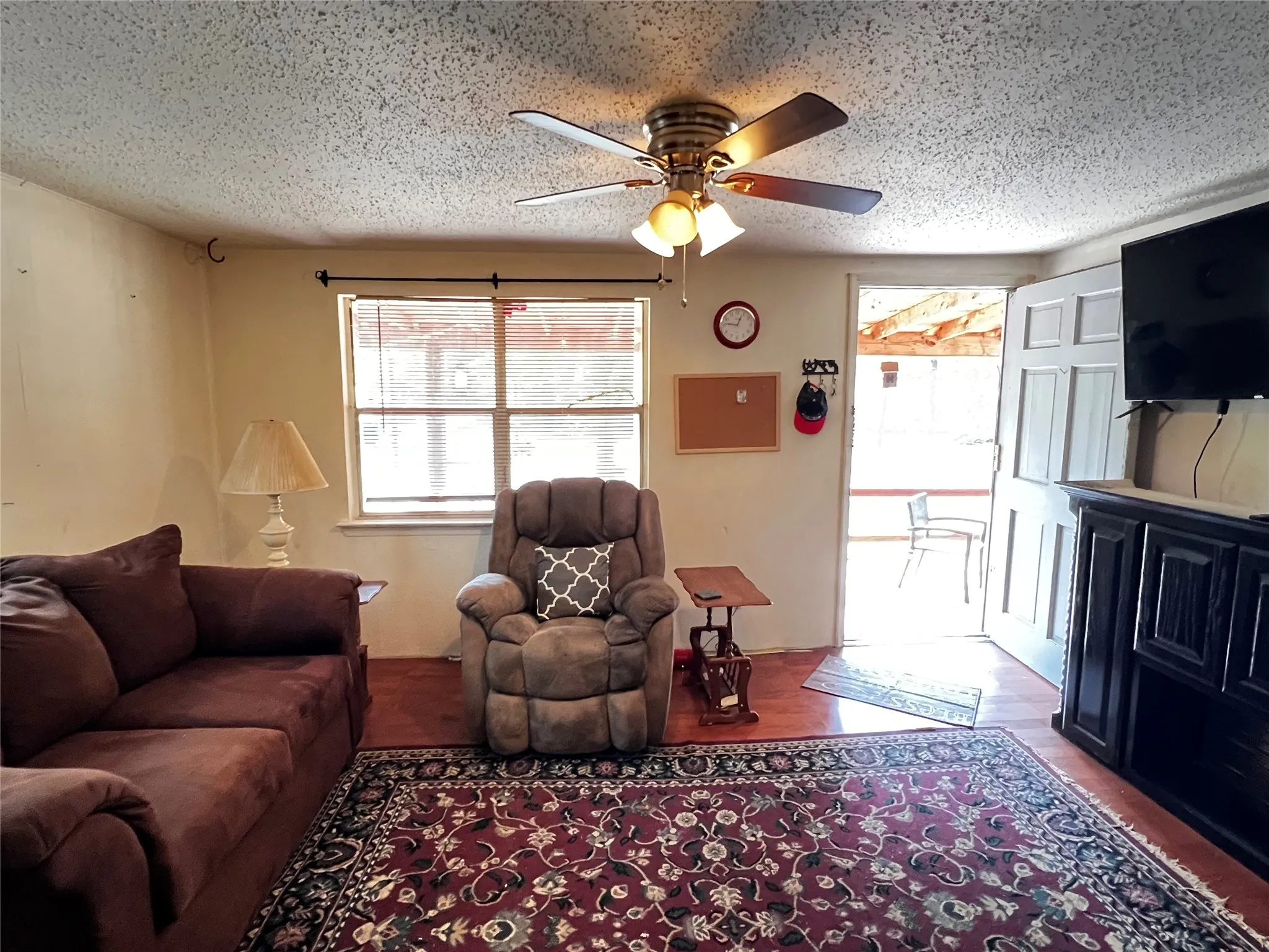 Wood-finish flooring throughout, featuring a multi-pane window with blinds, and a white paneled entry door with a screen door.