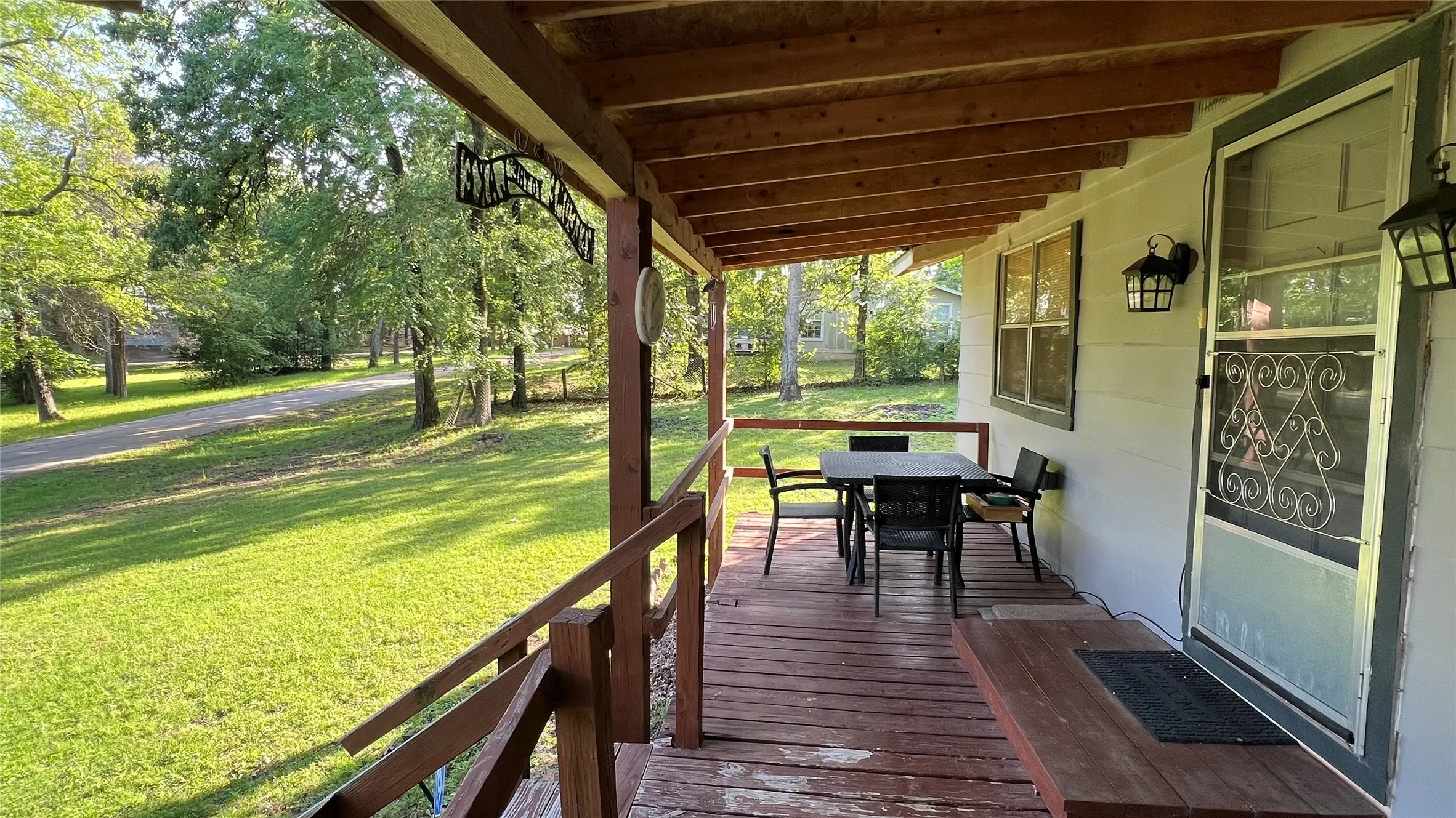 Spacious covered front porch featuring exposed wood beams and a wood decking.  Note second lot in the background.