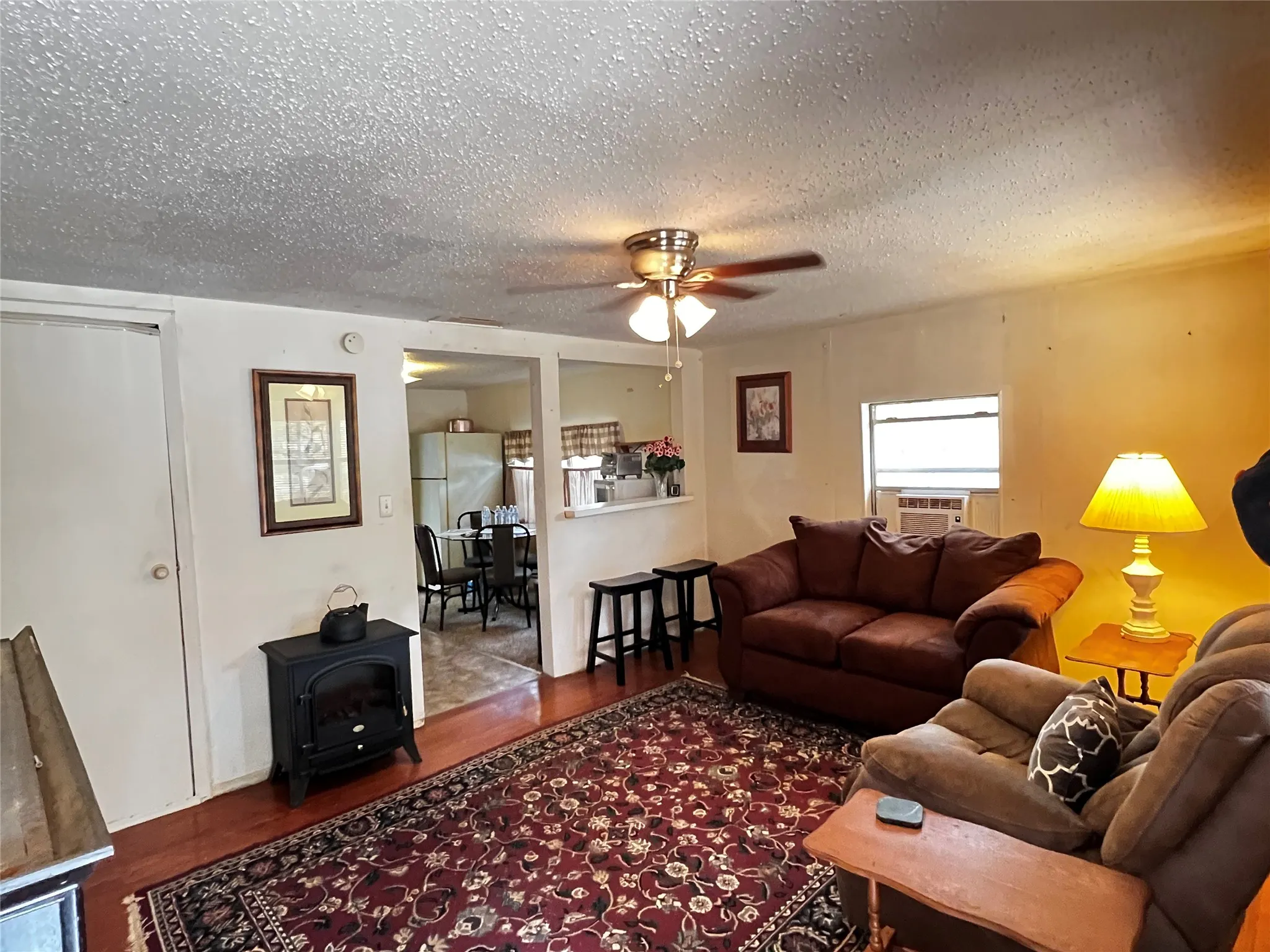 Living area featuring wood-finish flooring, a ceiling fan with integrated lighting, and an open pass-through to the kitchen