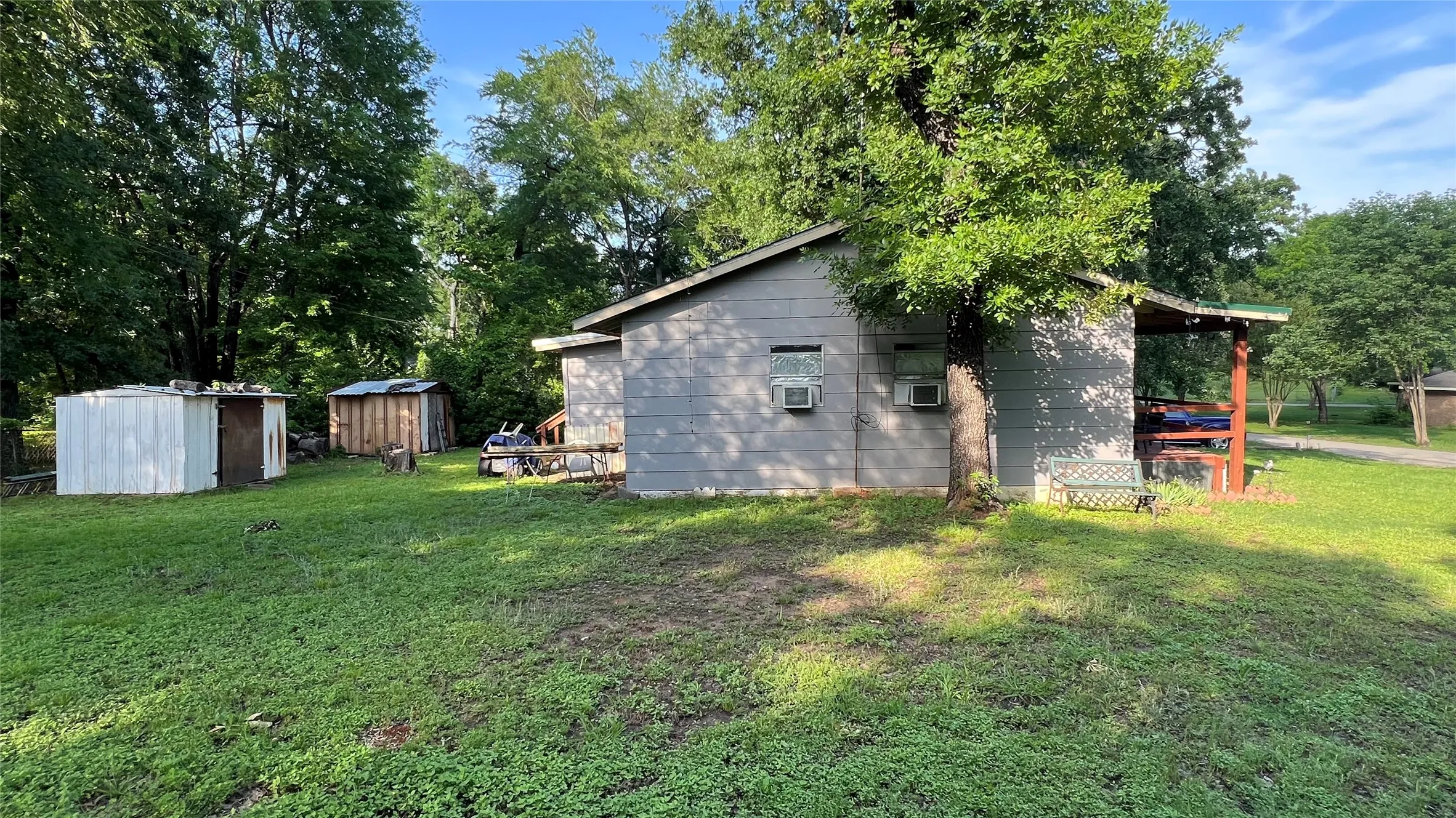 West side of the home showing the 2 bedrooms, each with a side window, plus the two storage buildings in the backyard