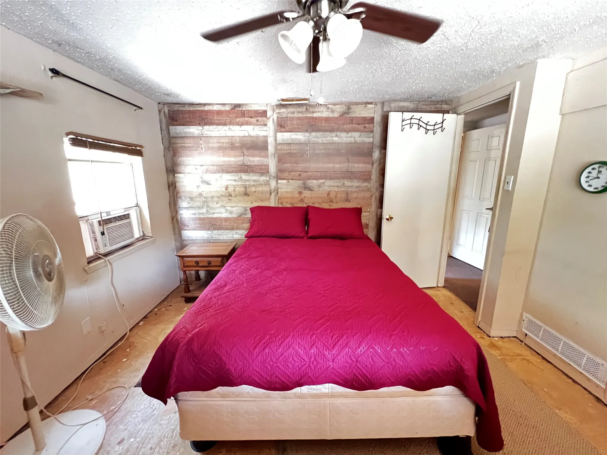 Front bedroom with wood-finish accent wall with a ceiling-mounted fan and integrated lighting