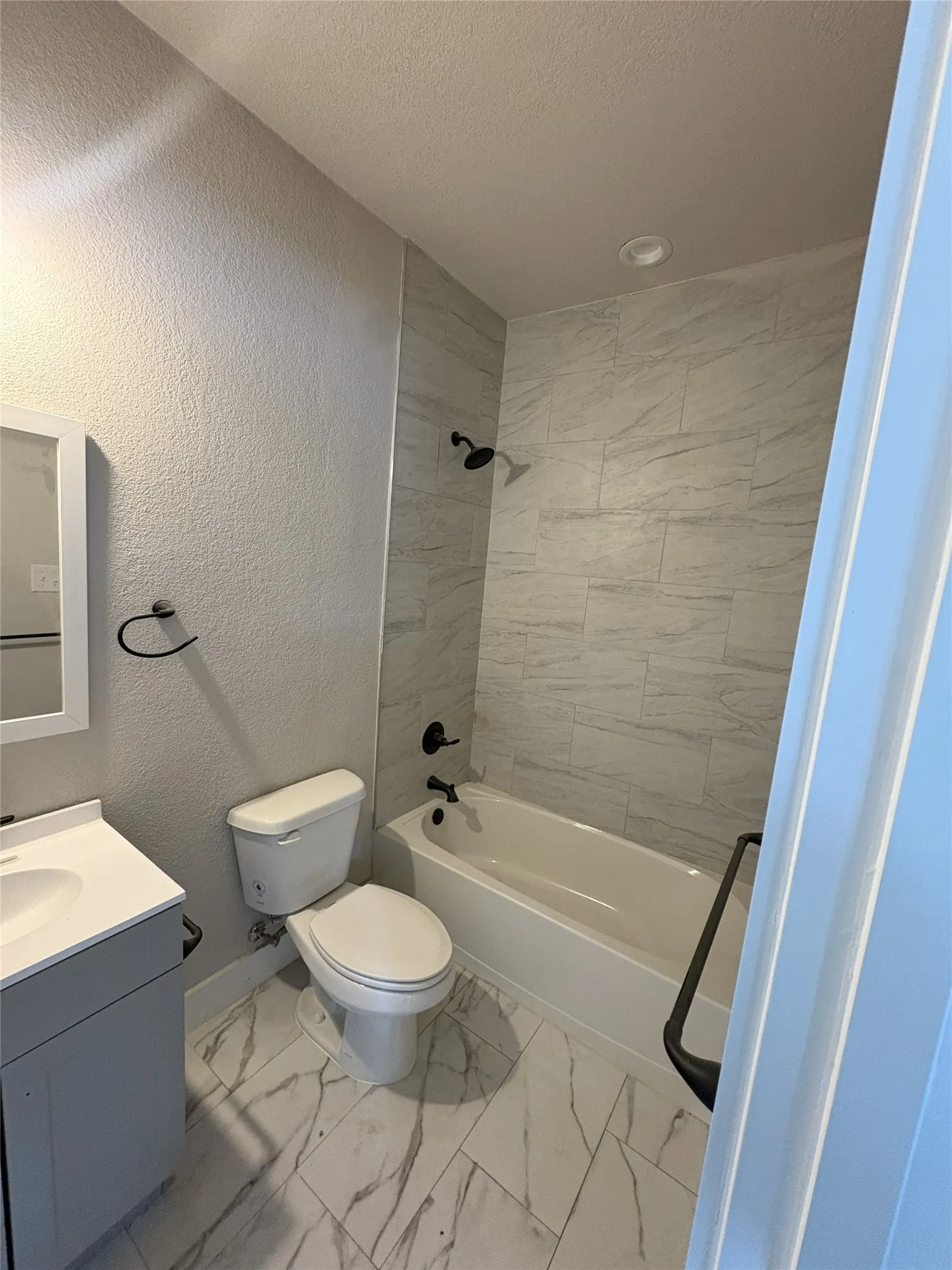 Bathroom featuring a tiled shower surround, integrated bathtub, and white vanity with a single basin