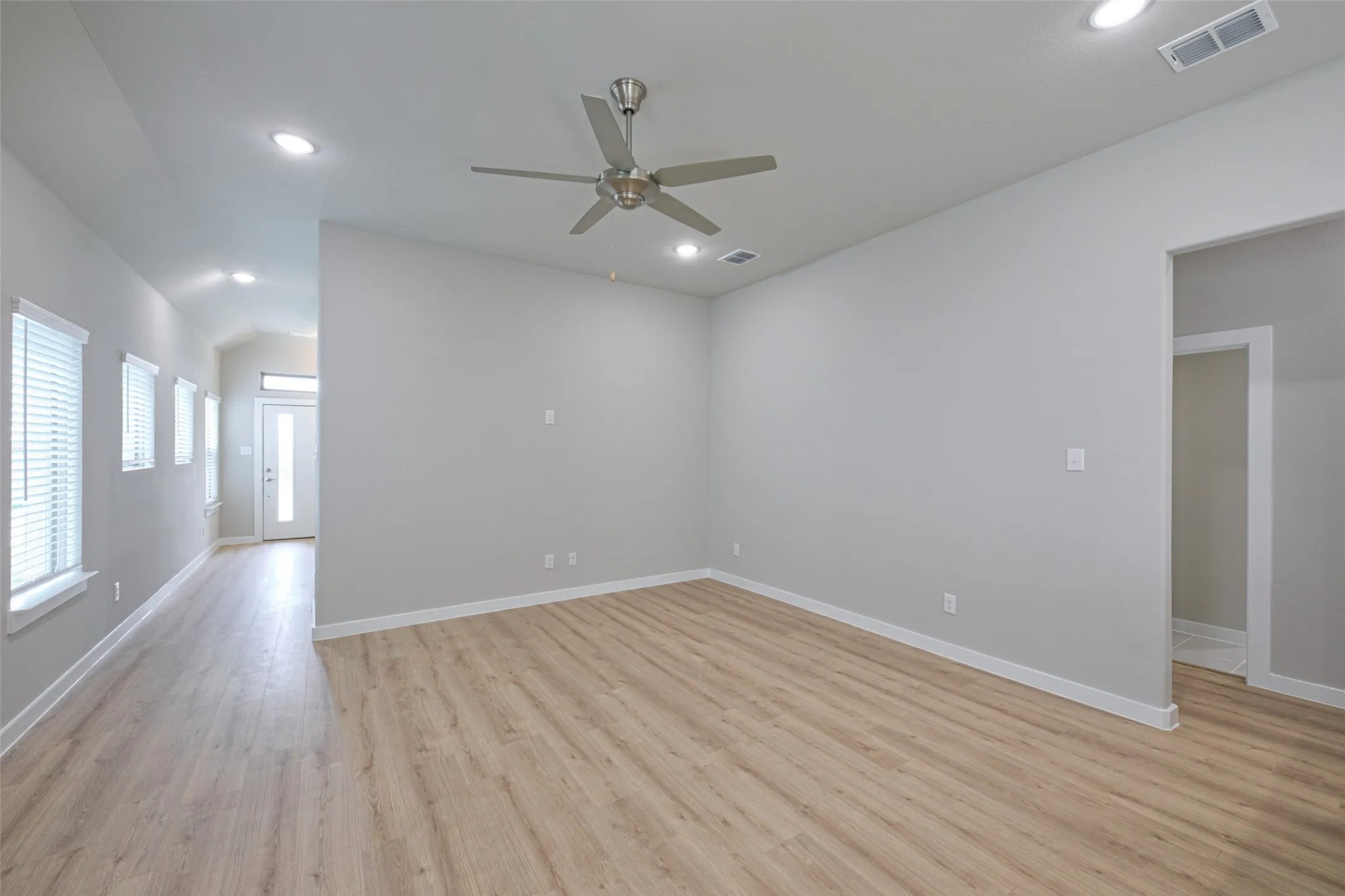 Spacious interior featuring wood-finish flooring, recessed lighting, a contemporary ceiling fan, and crisp white baseboards
