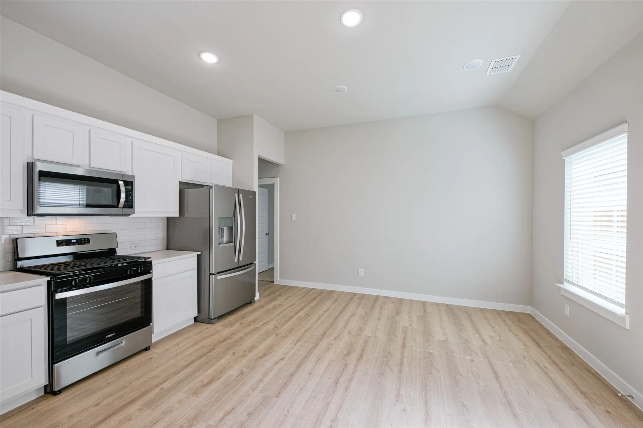 Modern kitchen featuring white shaker cabinetry, stainless steel appliances, and a subway tile backsplash