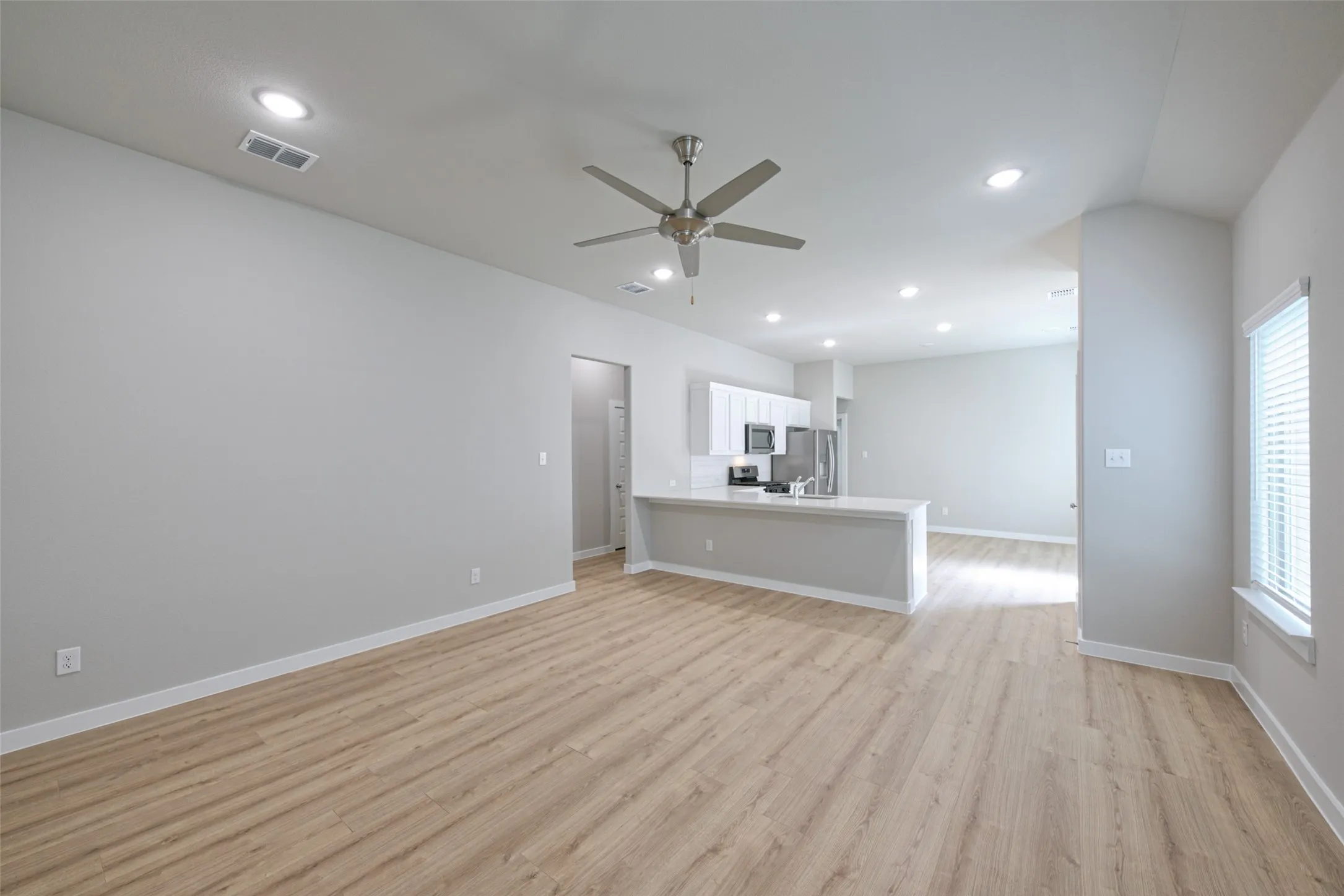 Open-concept living space featuring wood-finish flooring, recessed lighting, and a ceiling fan