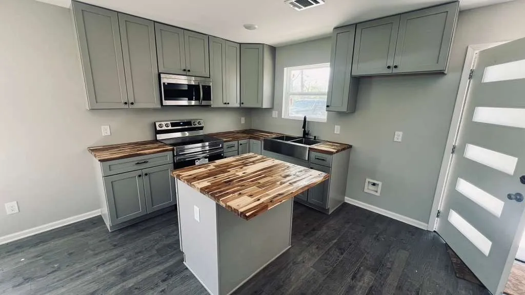 Kitchen featuring grey cabinetry, wood-finish countertops, stainless steel appliances, and a central island
