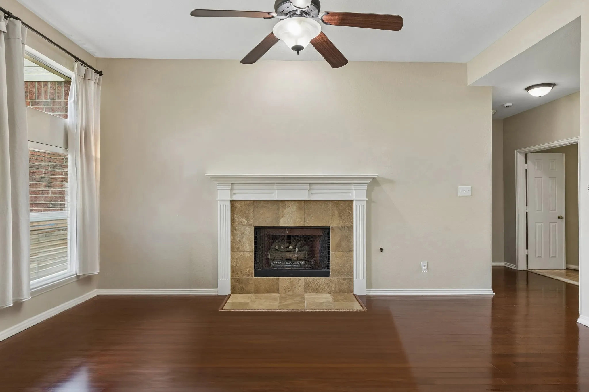 The family room is anchored by a fireplace with gas logs and stone surround. Other features include ceiling fan and hardwood flooring.