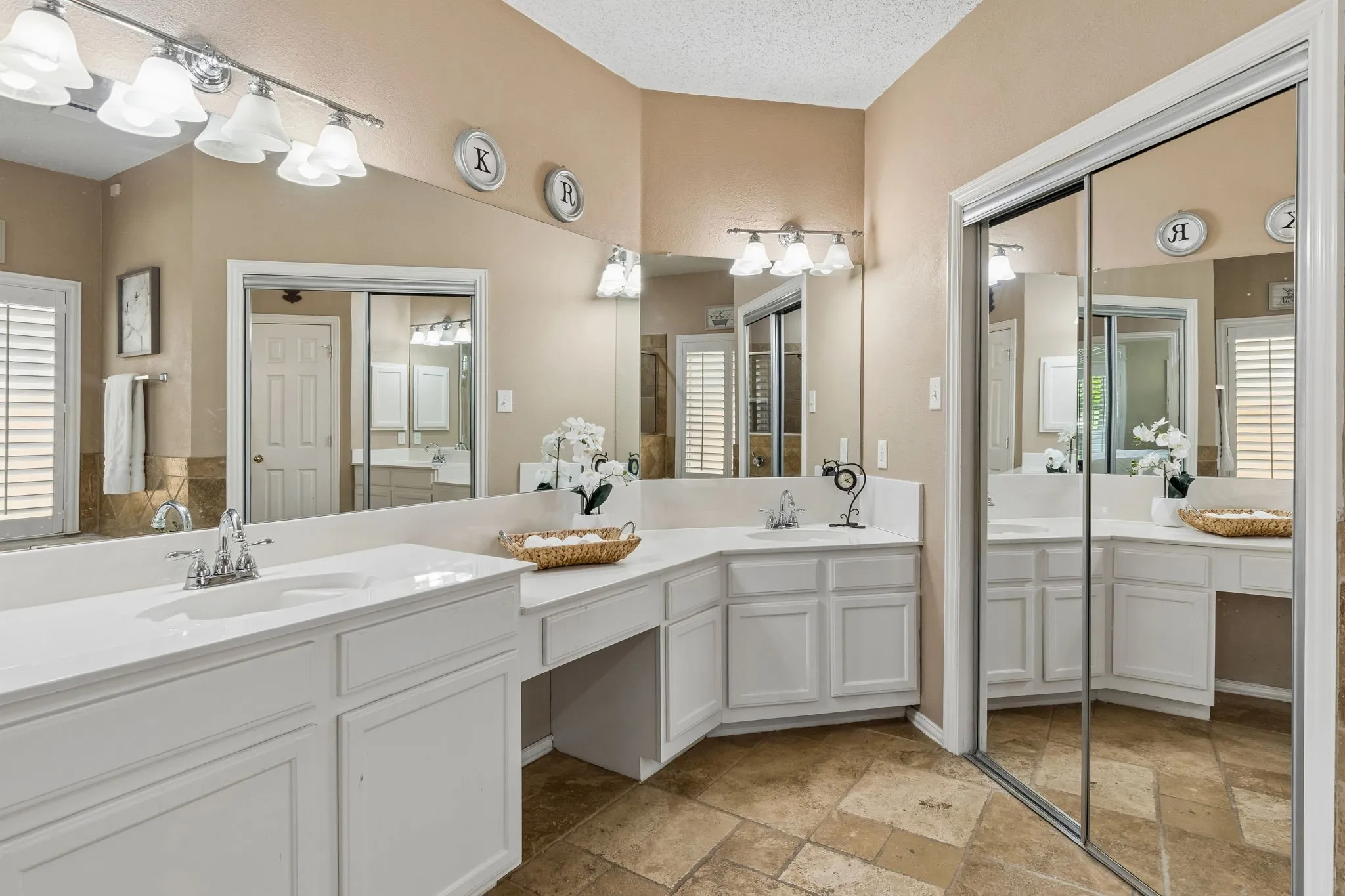 The primary bath offers dual vanities connected by a make up area, updated light fixtures and tile flooring.