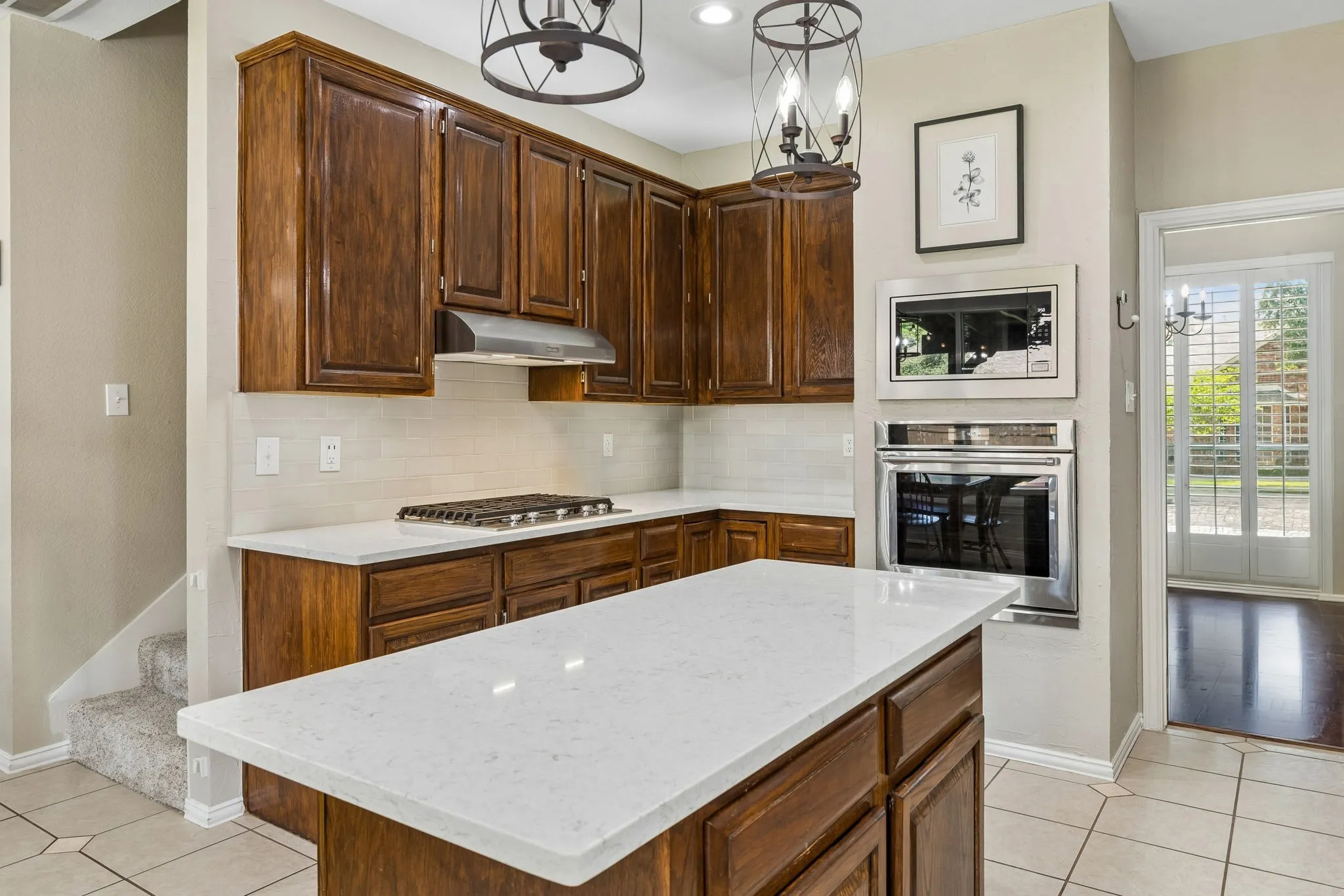 The beautifully updated kitchen offers quartz countertops, subway tile backsplash, handsome pendant lighting and direct acess to the dining room. New KitchenAid Microwave 2025, all other appliances 2019.
